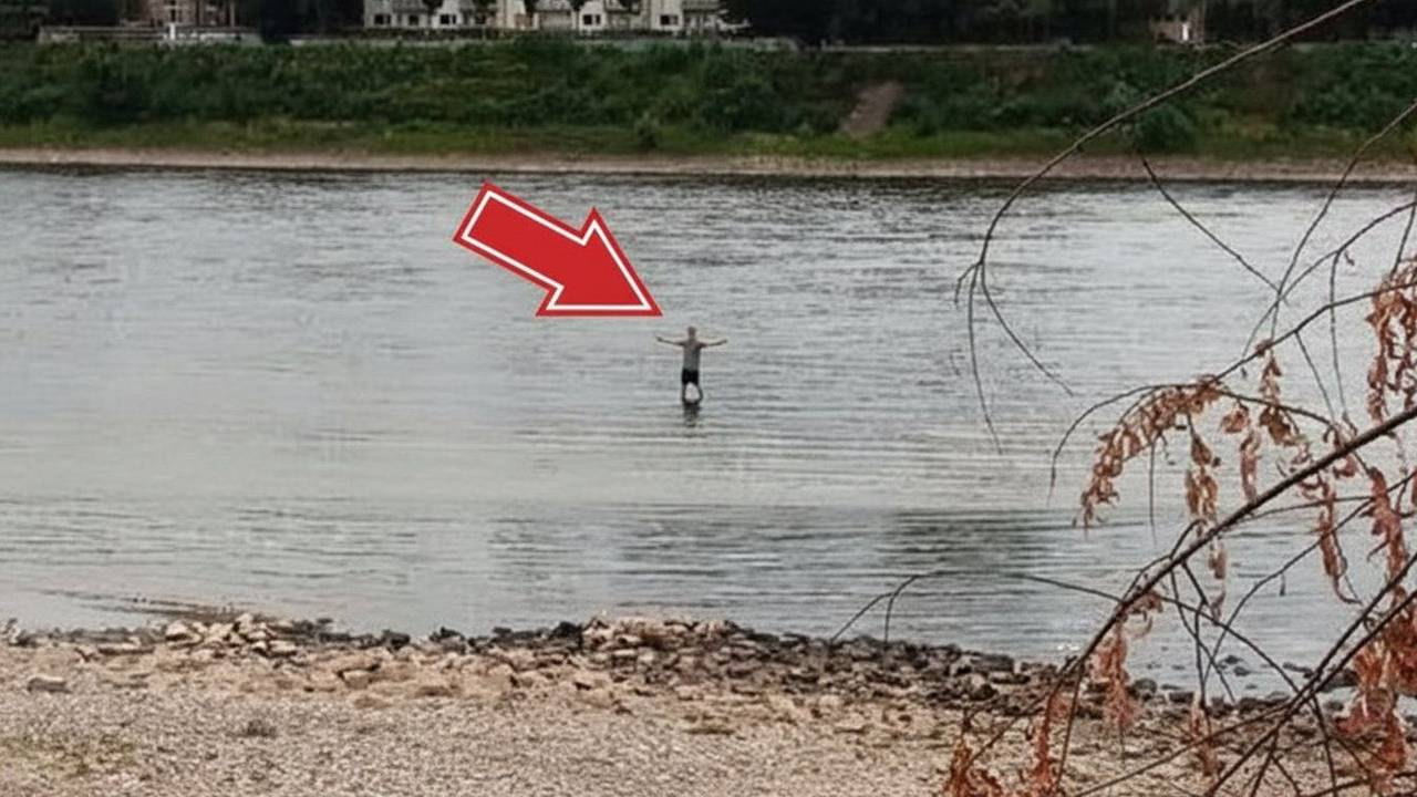 Ein Mann steht bei Niedrigwasser im Rhein in Köln-Niehl. Könnte man durch den Fluss laufen?