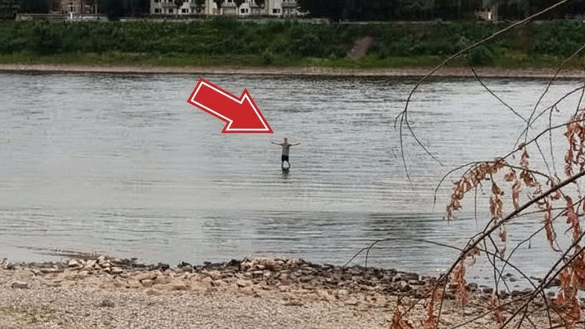 Ein Mann steht bei Niedrigwasser im Rhein in Köln-Niehl. Könnte man durch den Fluss laufen?