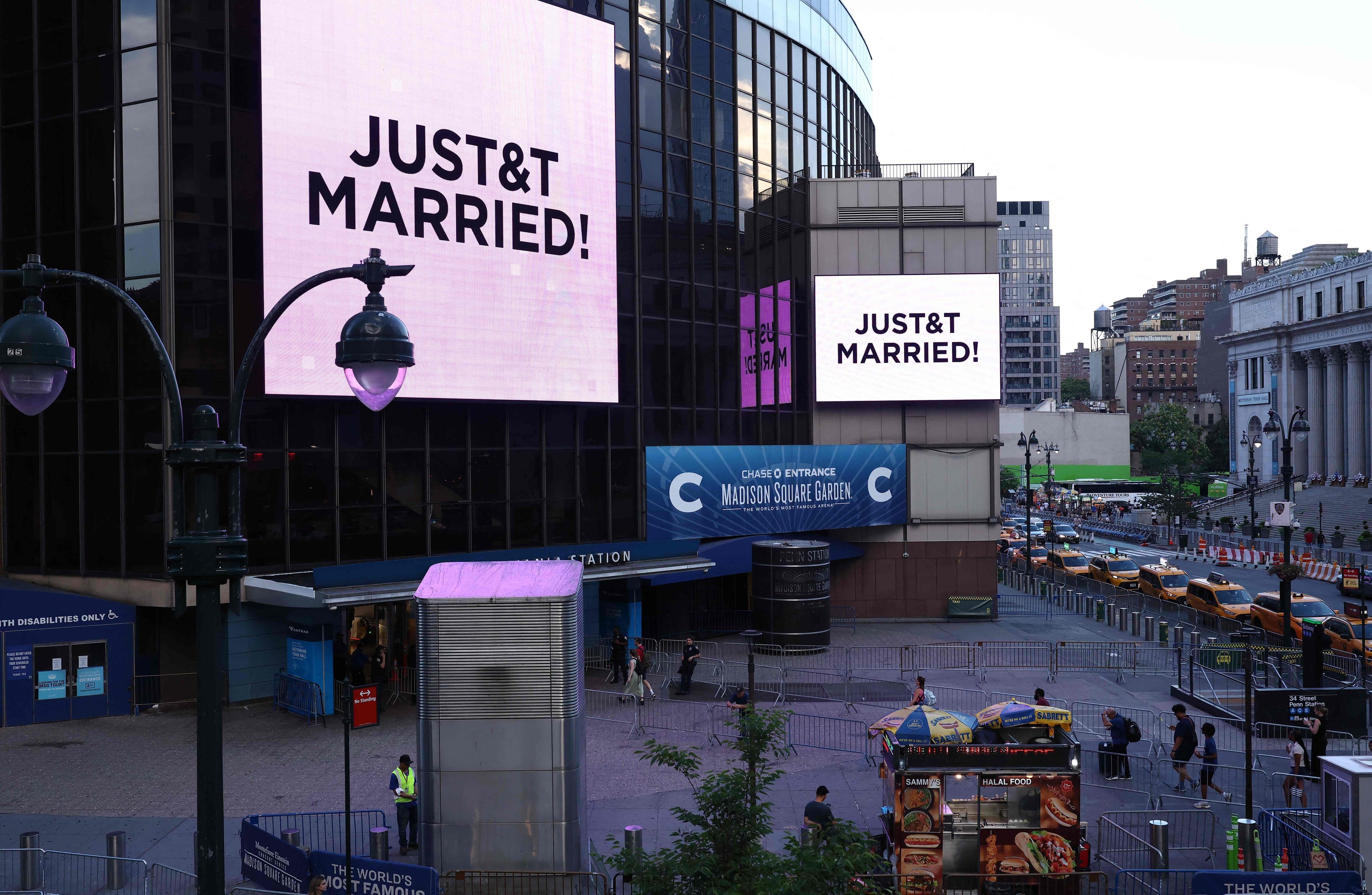 Vor dem Madison Square Garden, dem angeblichen Veranstaltungsort für die Hochzeitsfeierlichkeiten der Popsängerin Taylor Swift und des Profisportlers Travis Kelce, sind riesige Bildschirme zu sehen, auf denen die Botschaft „JUST&T MARRIED!“ (T&T steht für Taylor und Travis) zu lesen ist.