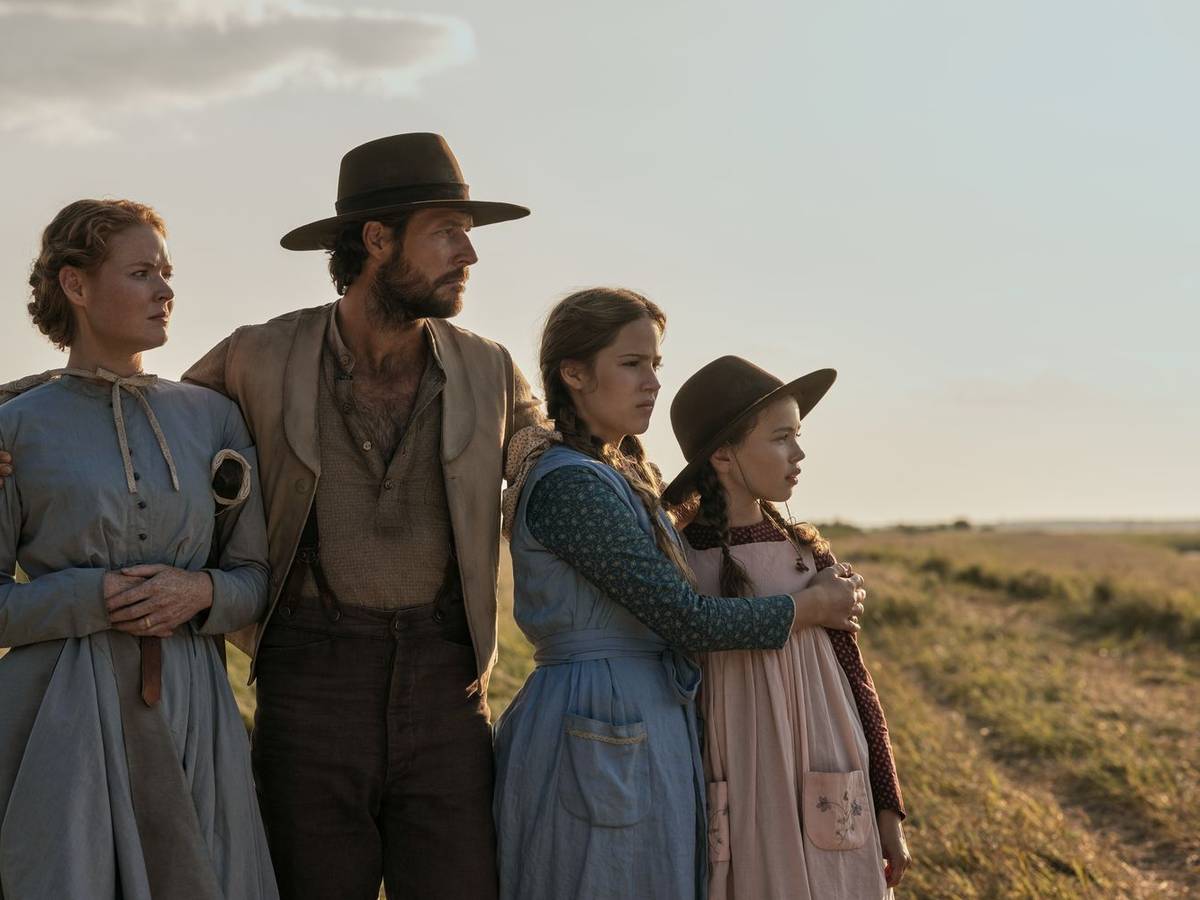 Familienvater Charles Ingalls (Luke Bracey) hat mit seiner Frau Caroline (Crosby Fitzgerald, links) und den Töchtern Mary (Skywalker Hughes, zweite von rechts) und Laura (Alice Halsey) ihre Heimat in Wisconsin verlassen, um in fruchtbarerem Land, das von der Regierung als frei versprochen wurde, ein neues Leben zu beginnen. (Bild: Eric Zachanowich/Netflix © 2026)