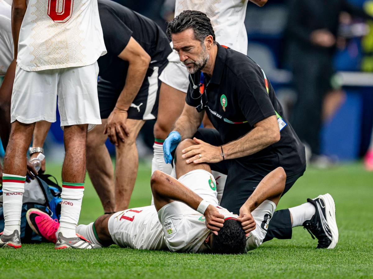 Marokkos Ismael Saibari liegt verletzt auf dem Rasen und wird von einem Physio behandelt. Dabei hat er sein Gesicht unter dem Trikot versteckt.
