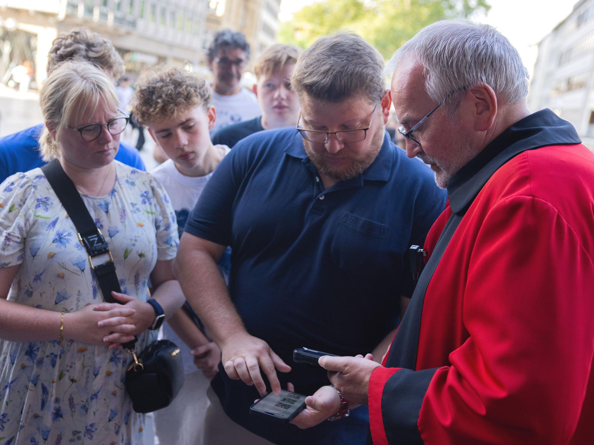 Ein Domschweizer (r) kontrolliert Tickets vor dem Haupteingang des Kölner Doms.