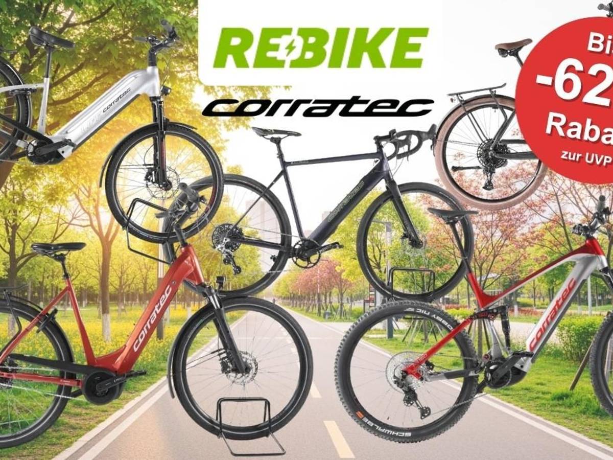 Mehrere Corratec E‑Bikes unterschiedlicher Typen – darunter Trekking-, City- und Mountainbikes – vor einer Landstraße an einem sonnigen Tag, die durch grüne Natur führt.