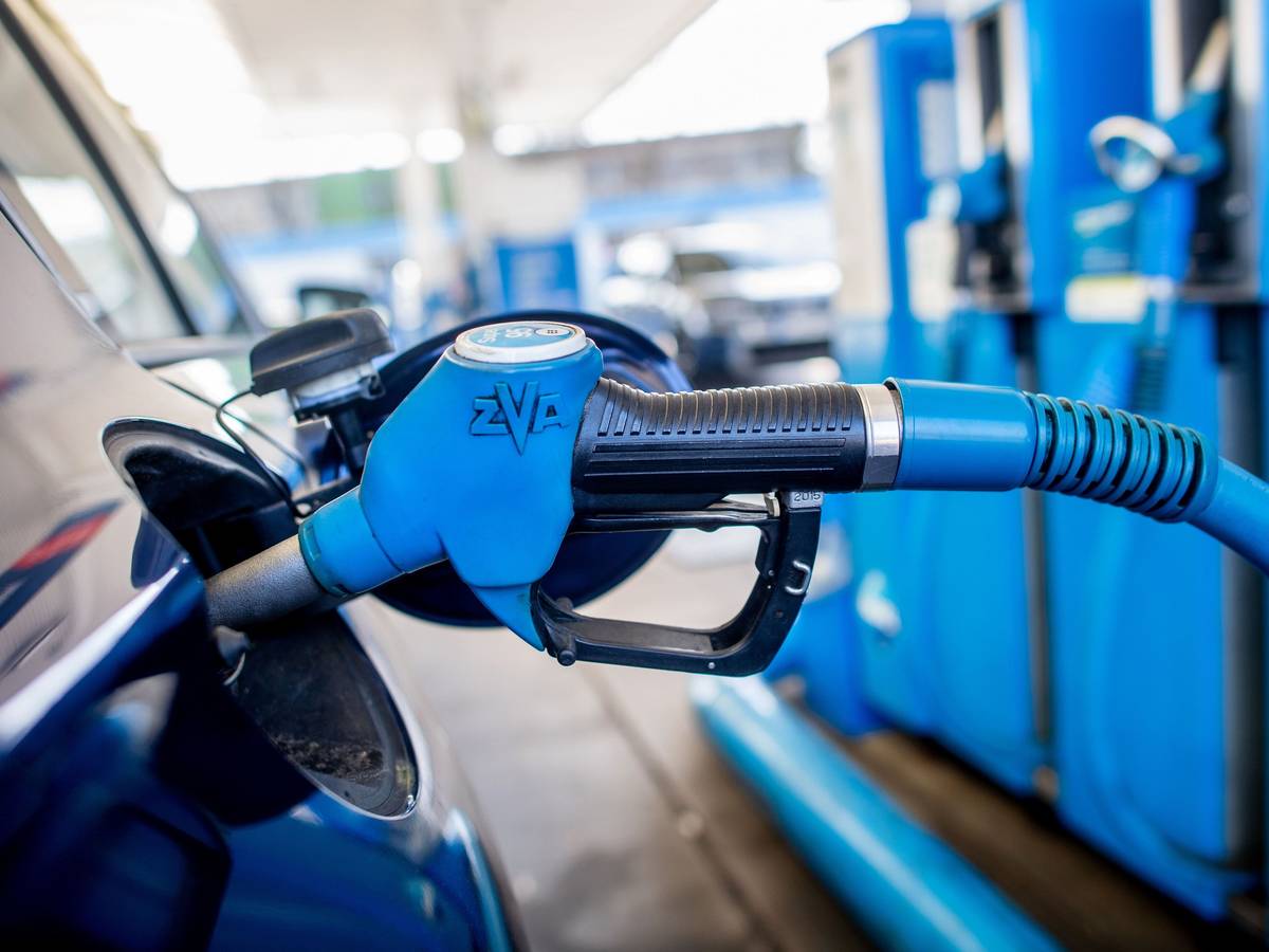 Eine Zapfpistole mit der Aufschrift „Super 95“ steckt an einer Tankstelle in der Tanköffnung eines Fahrzeugs.