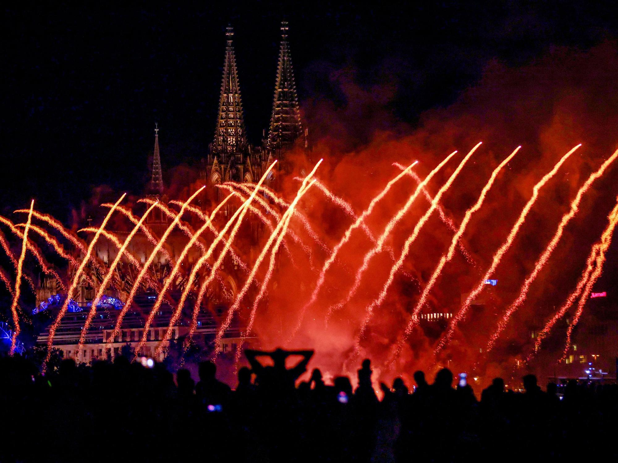 Blick auf die Kölner Lichter. Menschen betrachten das musiksynchrone Feuerwerk.