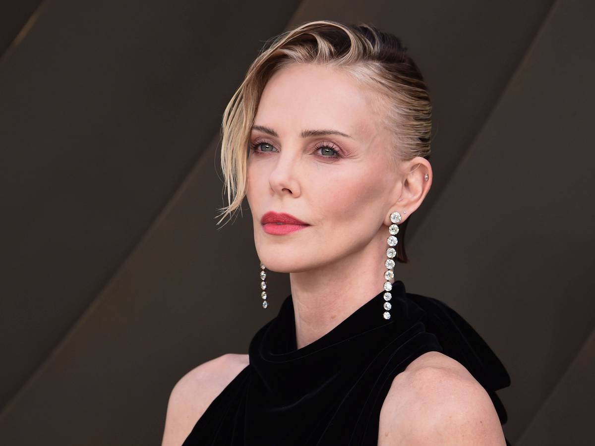 Charlize Theron mit dunklem Oberteil und Schmuck