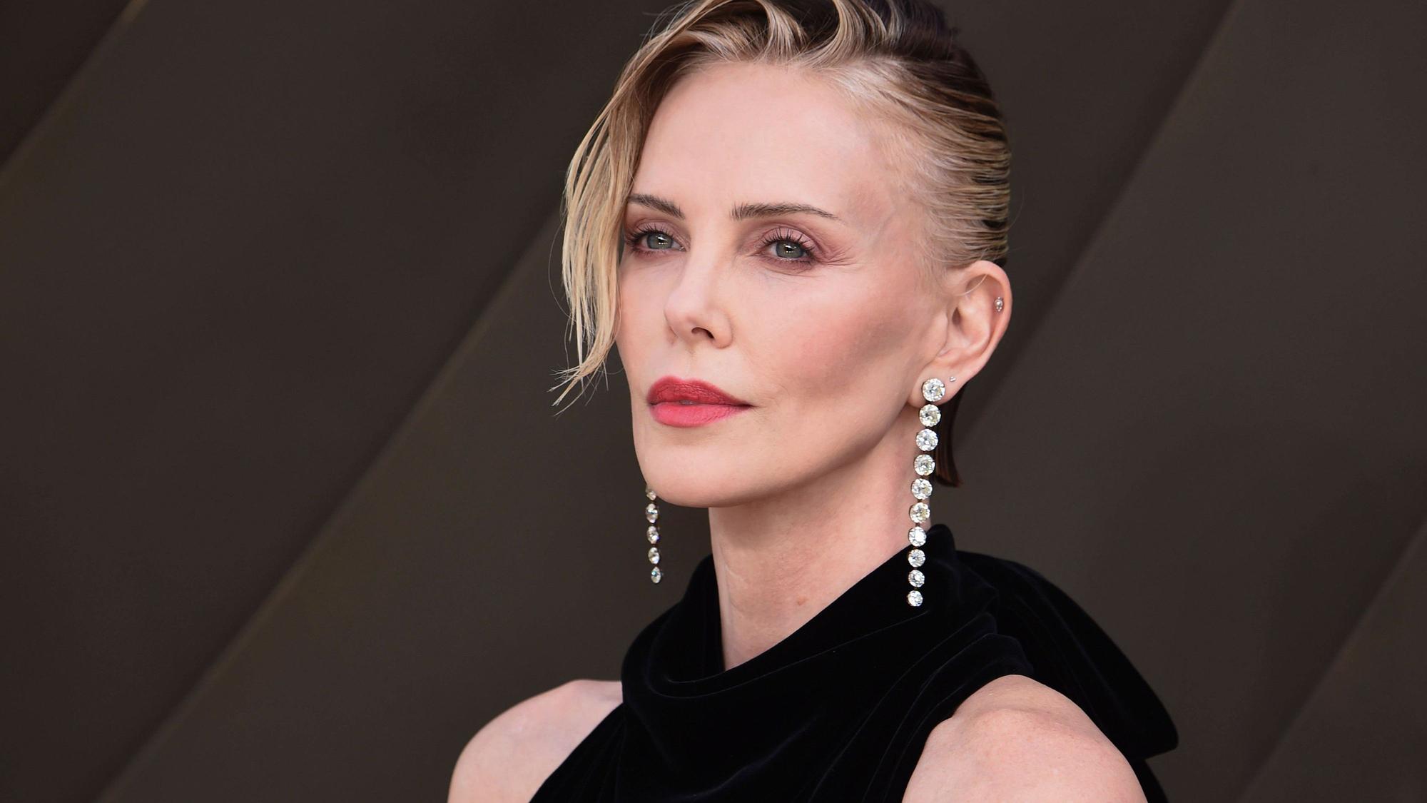 Charlize Theron mit dunklem Oberteil und Schmuck