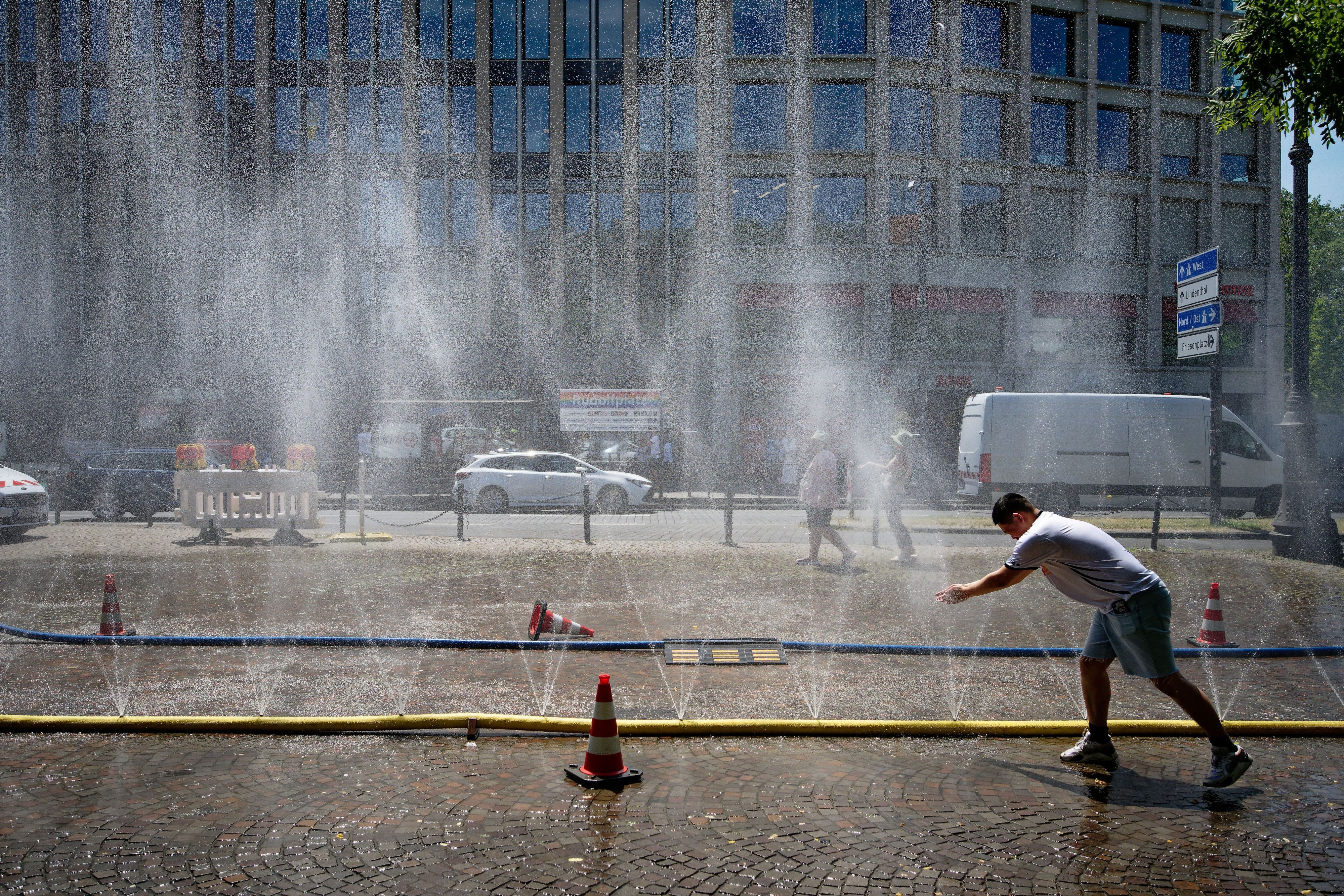 Passanten genießen Ende Juni Wasserfontänen, die im Rahmen der Hitzeaktion „Cooling Cologne“ der Stadt Köln auf dem Rudolfplatz in der Innenstadt installiert wurden.