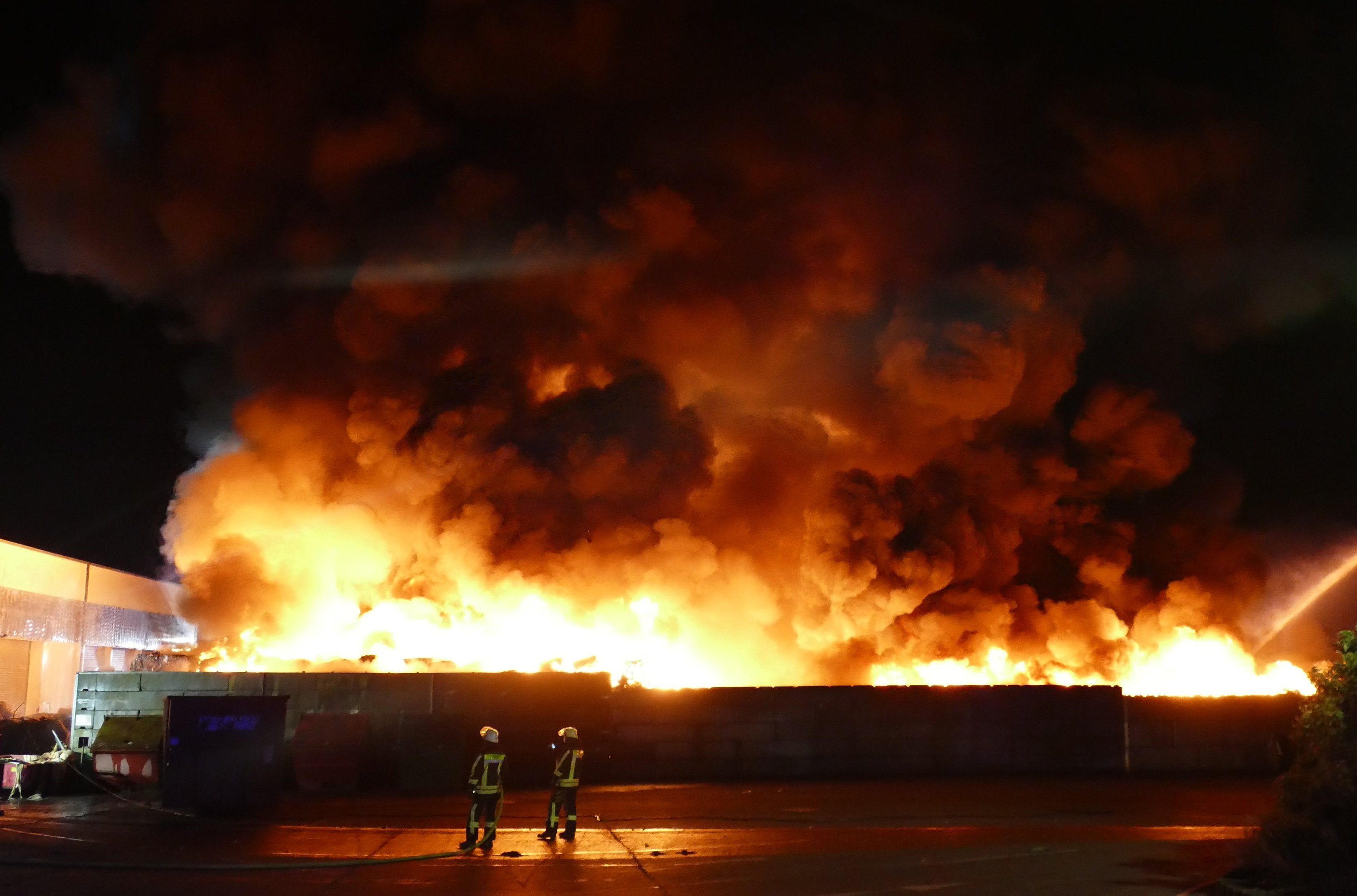 Feuerwehrleute bekämpfen einen Brand auf einem Wertstoffhof im Rhein-Sieg-Kreis. Dort hat eine große Menge Kunststoffmüll Feuer gefangen.