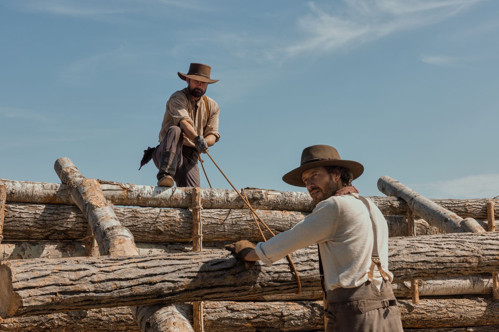 Das „Little House on the Prairie“ (Auf Deutsch: „Das kleine Haus in der Prärie“) baut sich nicht von alleine. Charles Ingalls (Luke Bracey, rechts) bekommt dabei Hilfe von John Edwards (Warren Christie). Er wurde den Ingalls' auch in der ersten Serienadaption ein guter Freund. Er ist in Laura Ingalls Wilders Büchern sehr locker an eine wahre Person angelehnt.  (Bild: Eric Zachanowich/Netflix © 2026)