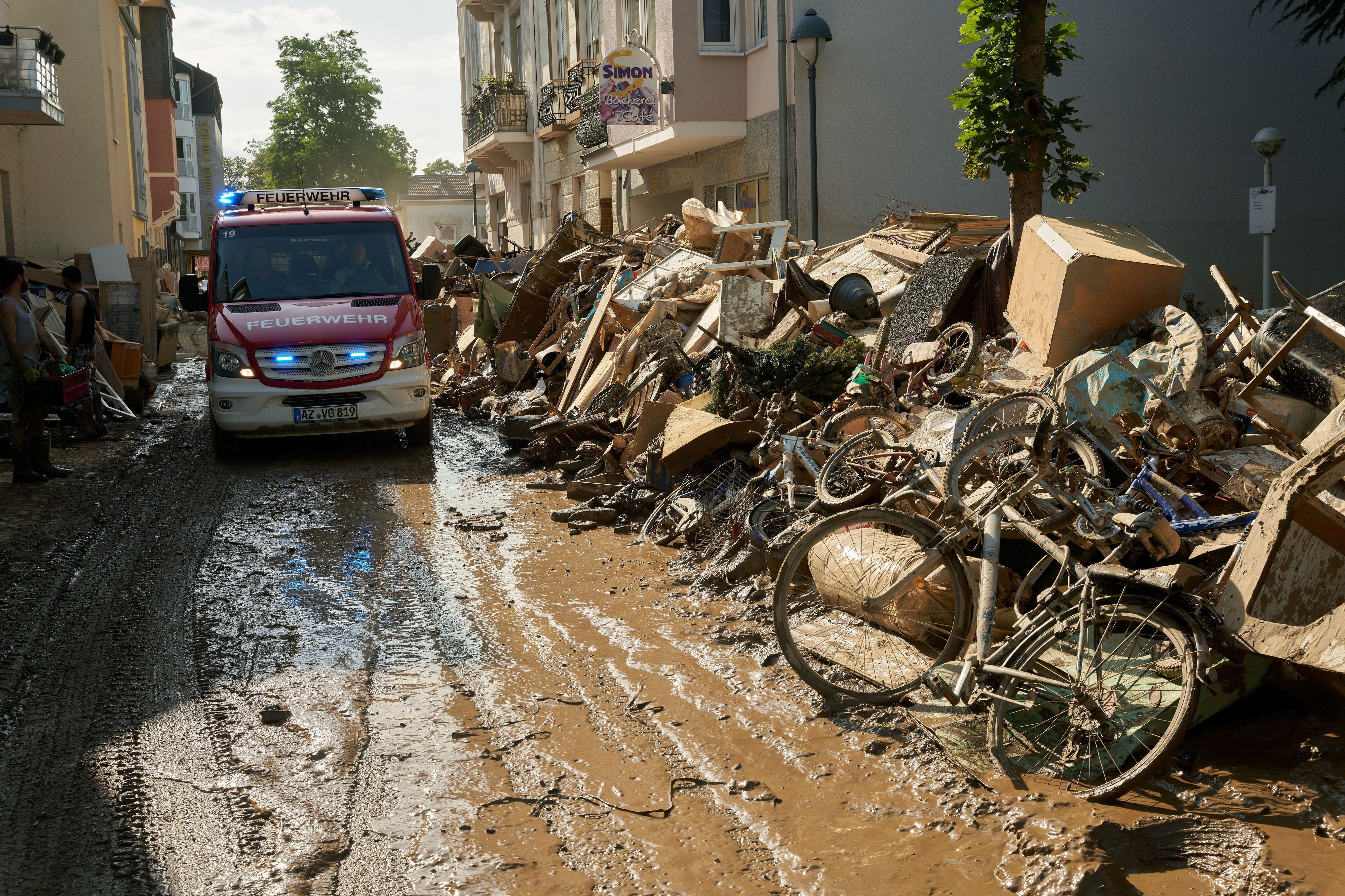 Ein Einsatzwagen der Feuerwehr fährt am 18. Juli 2021 durch eine Straße in Bad Neuenahr, die mit Sperrmüll gesäumt ist.