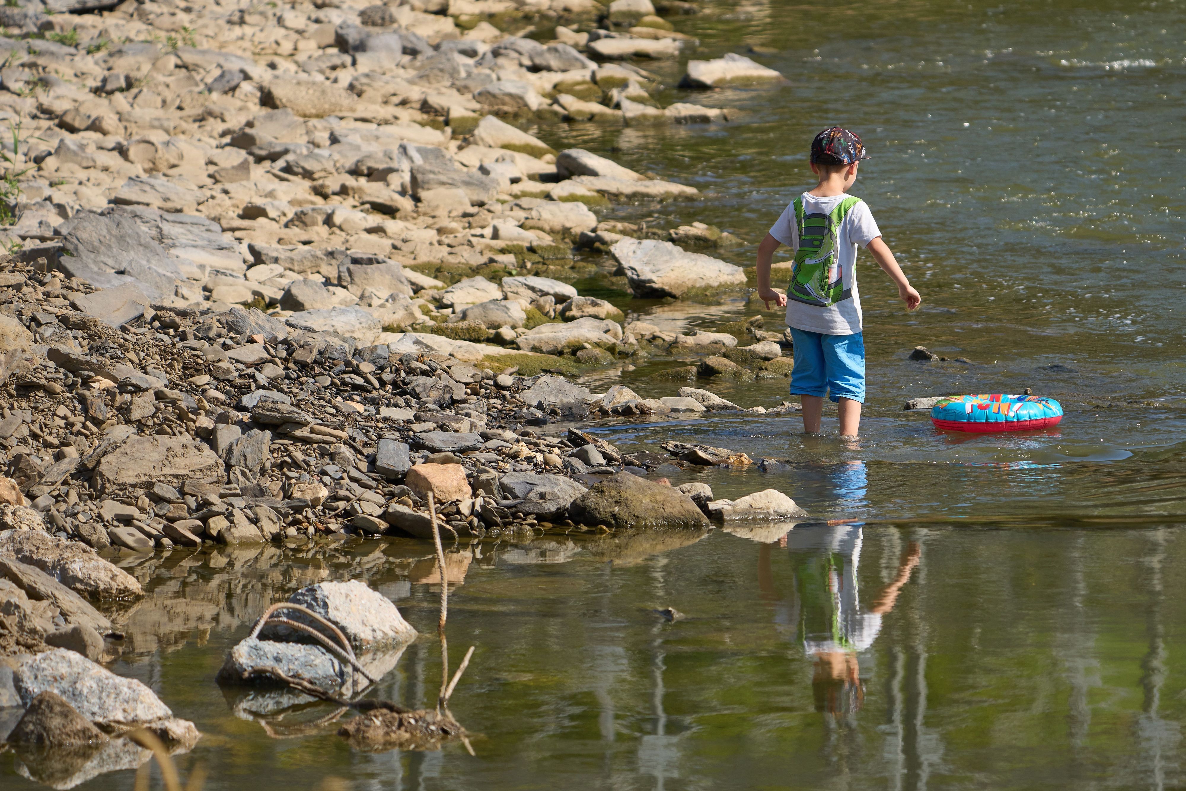 Kinder laufen bei Niedrigwasser über die Hungersteine der Ahr bei Laach.