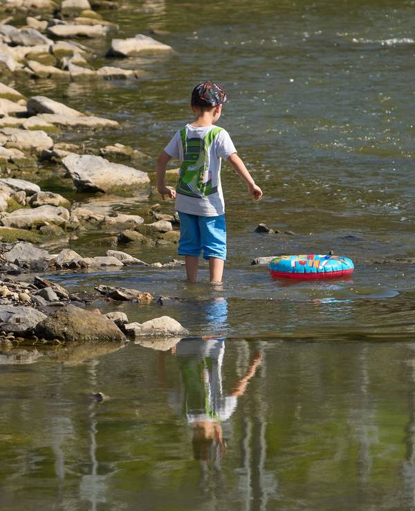 Kinder laufen bei Niedrigwasser über die Hungersteine der Ahr bei Laach.