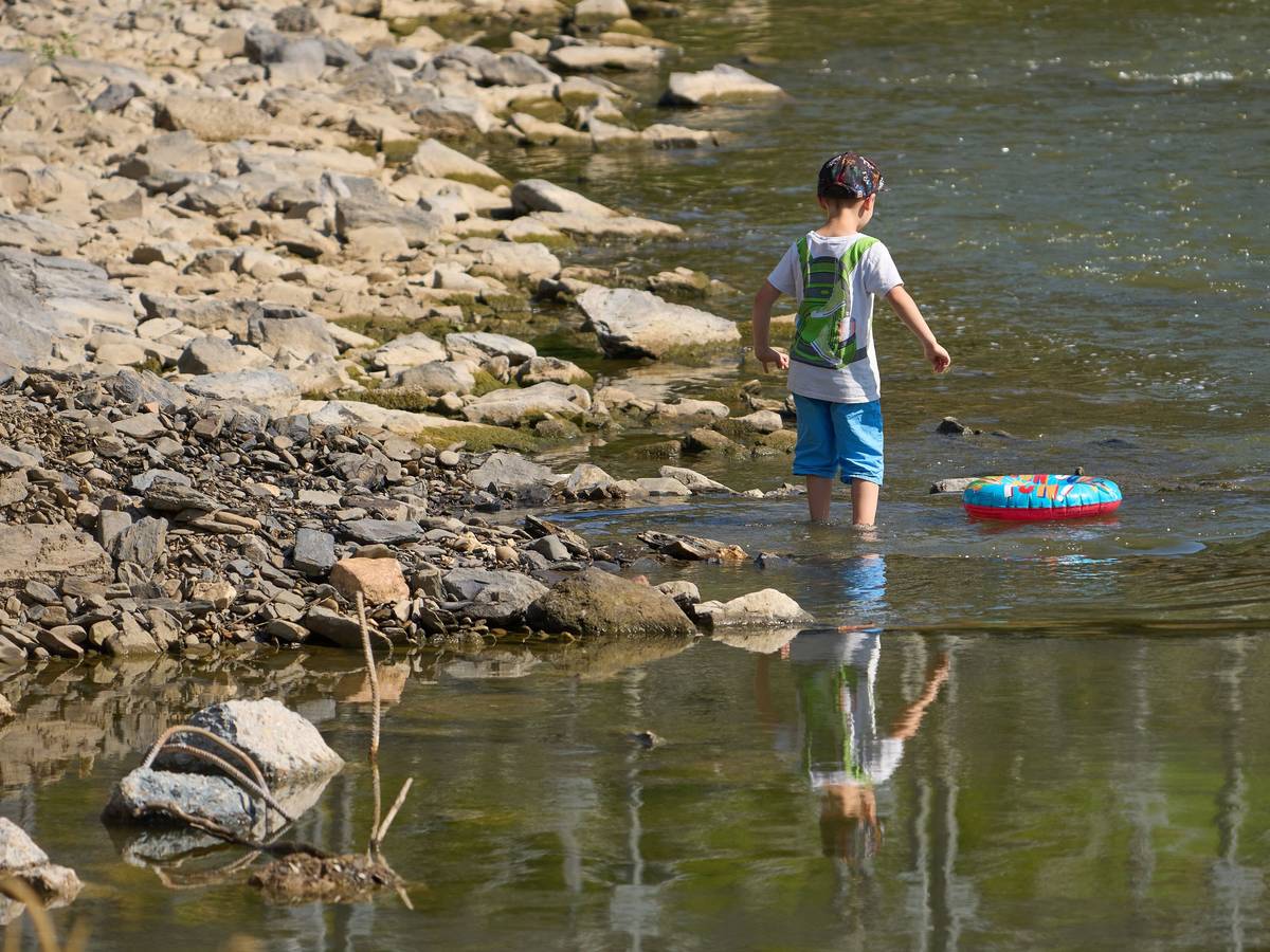 Kinder laufen bei Niedrigwasser über die Hungersteine der Ahr bei Laach.