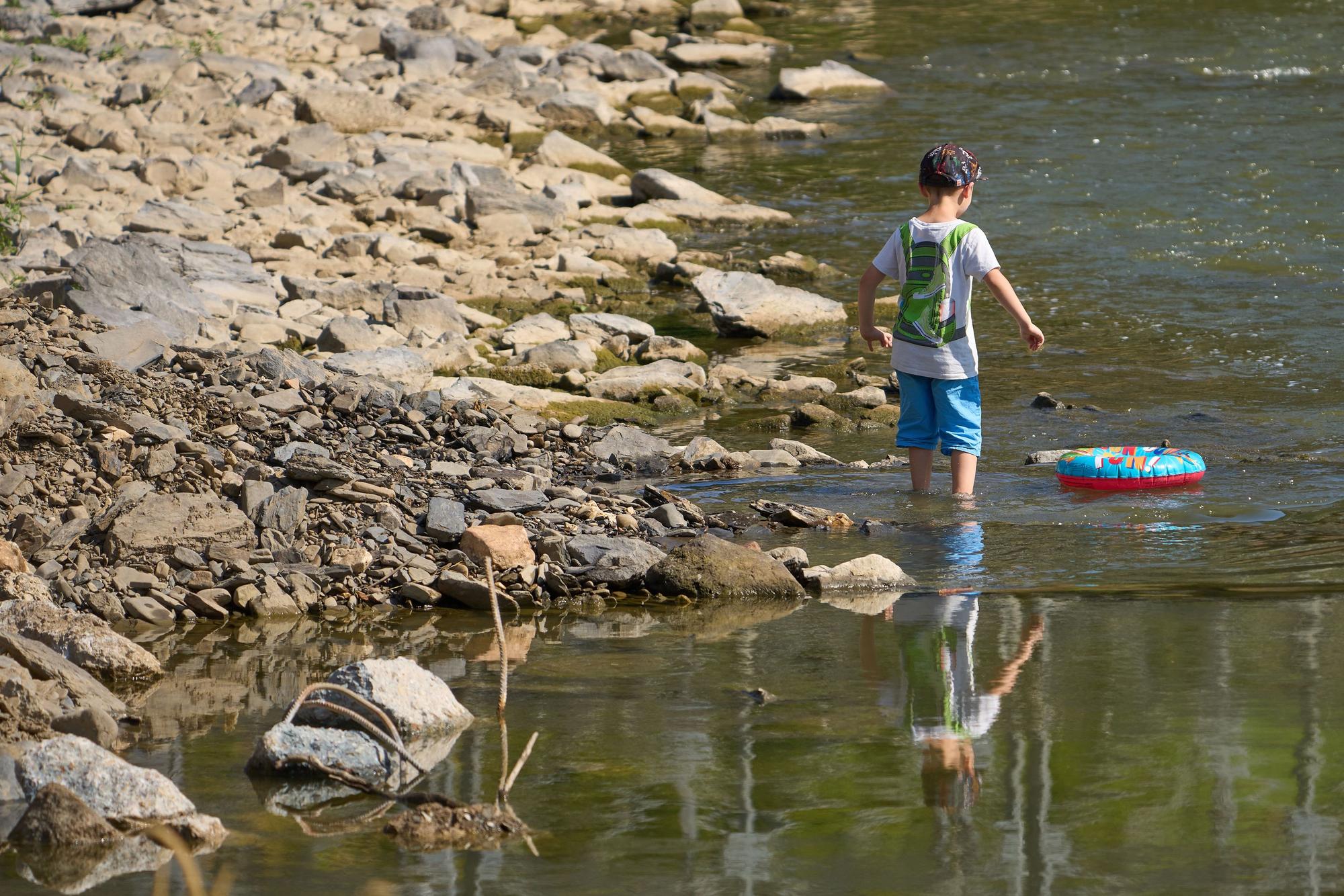 Kinder laufen bei Niedrigwasser über die Hungersteine der Ahr bei Laach.