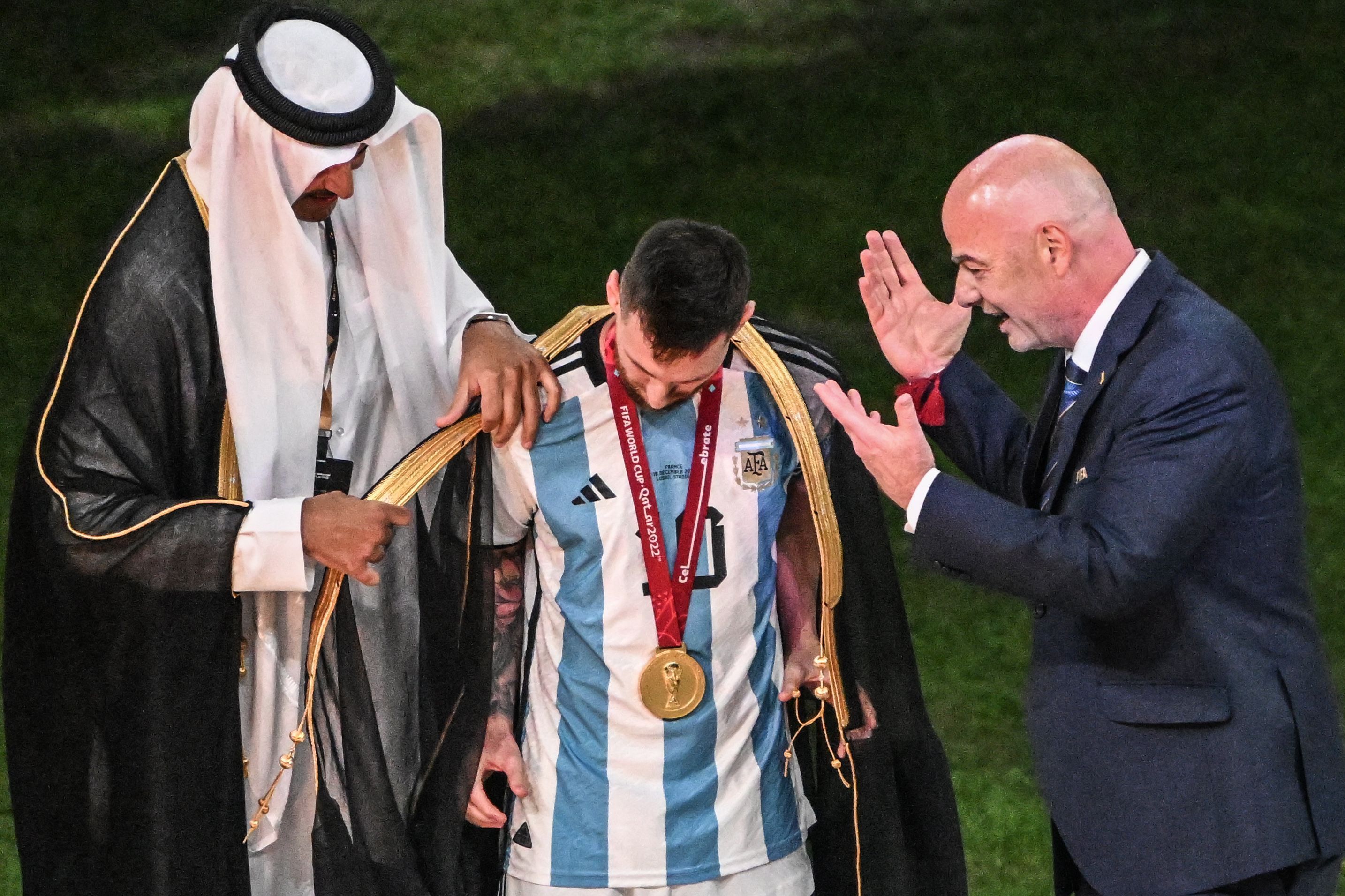 Der Emir von Katar, Scheich Tamim bin Hamad Al Thani, legt Argentiniens Lionel Messi vor Übergabe des WM-Pokals vor Fifa-Präsident Gianni Infantino ein Bischt, ein traditionelles arabische Kleidungsstück an.