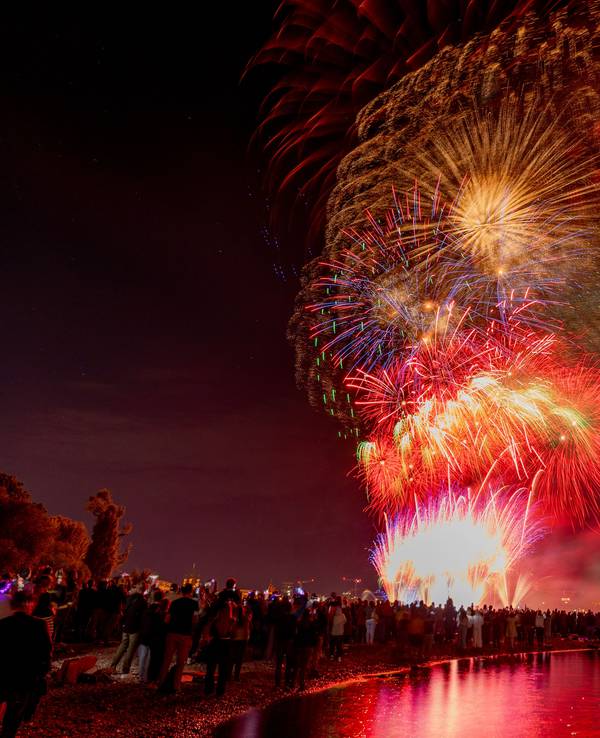 Menschen besuchen im Kölner Rheinpark das größte musiksynchrone Feuerwerk Europas.
