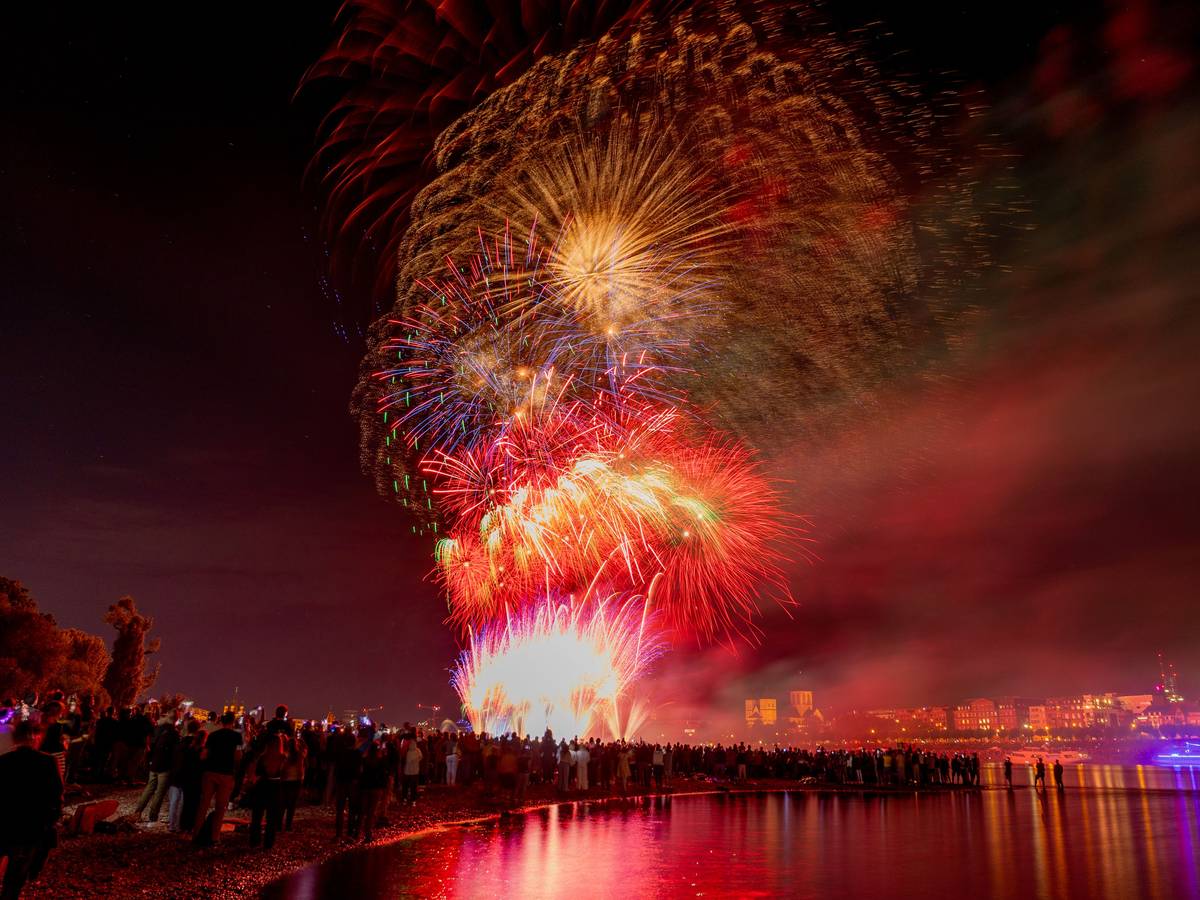 Menschen besuchen im Kölner Rheinpark das größte musiksynchrone Feuerwerk Europas.