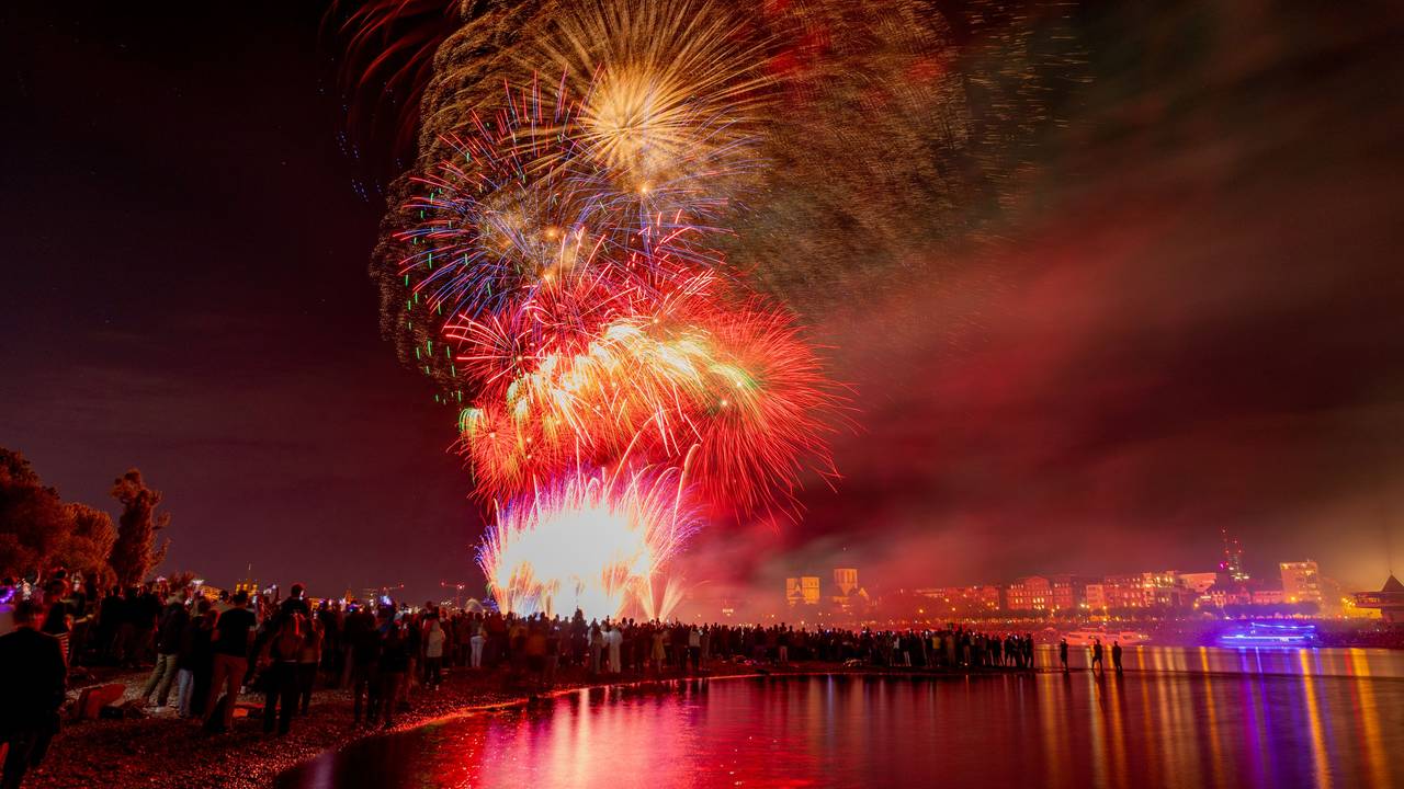 Menschen besuchen im Kölner Rheinpark das größte musiksynchrone Feuerwerk Europas.
