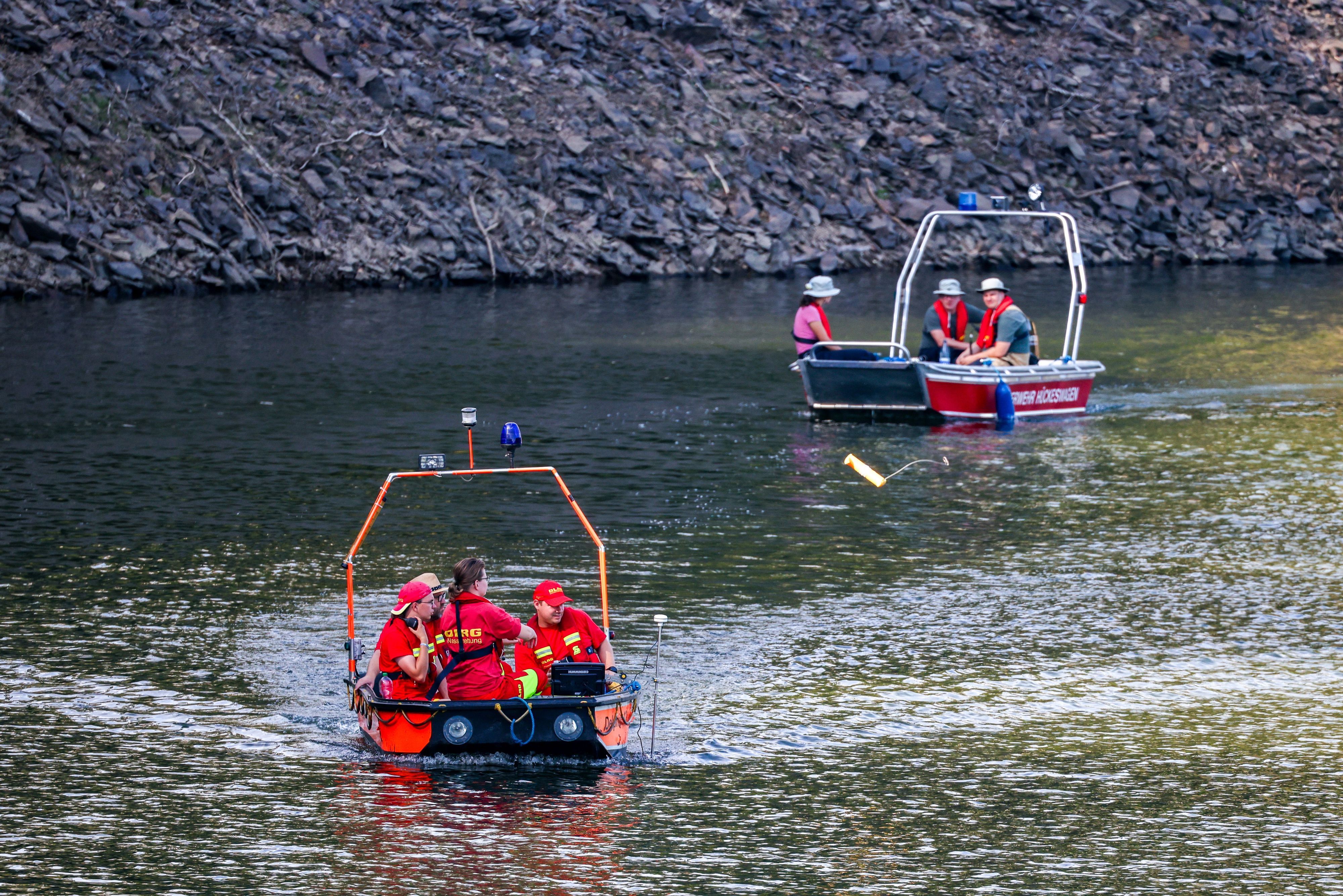 Boote der Deutschen Lebens-Rettungs-Gesellschaft (DLRG) und der Feuerwehr fahren am 12. Juli bei der Suche nach einer vermissten Person in der Wuppertalsperre auf dem Wasser entlang.