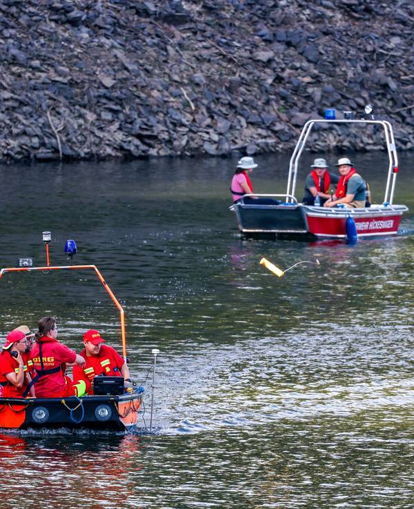 Boote der Deutschen Lebens-Rettungs-Gesellschaft (DLRG) und der Feuerwehr fahren am 12. Juli bei der Suche nach einer vermissten Person in der Wuppertalsperre auf dem Wasser entlang.