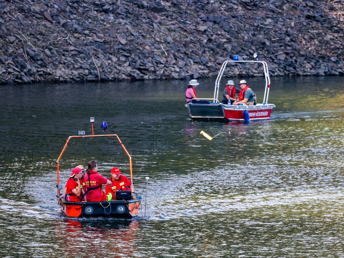 Boote der Deutschen Lebens-Rettungs-Gesellschaft (DLRG) und der Feuerwehr fahren am 12. Juli bei der Suche nach einer vermissten Person in der Wuppertalsperre auf dem Wasser entlang.