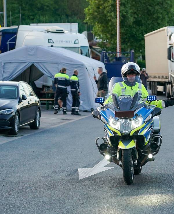 Ein Motorrad-Polizist vor einem Lkw.