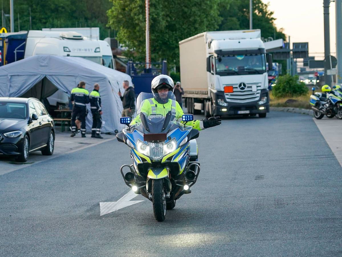 Ein Motorrad-Polizist vor einem Lkw.