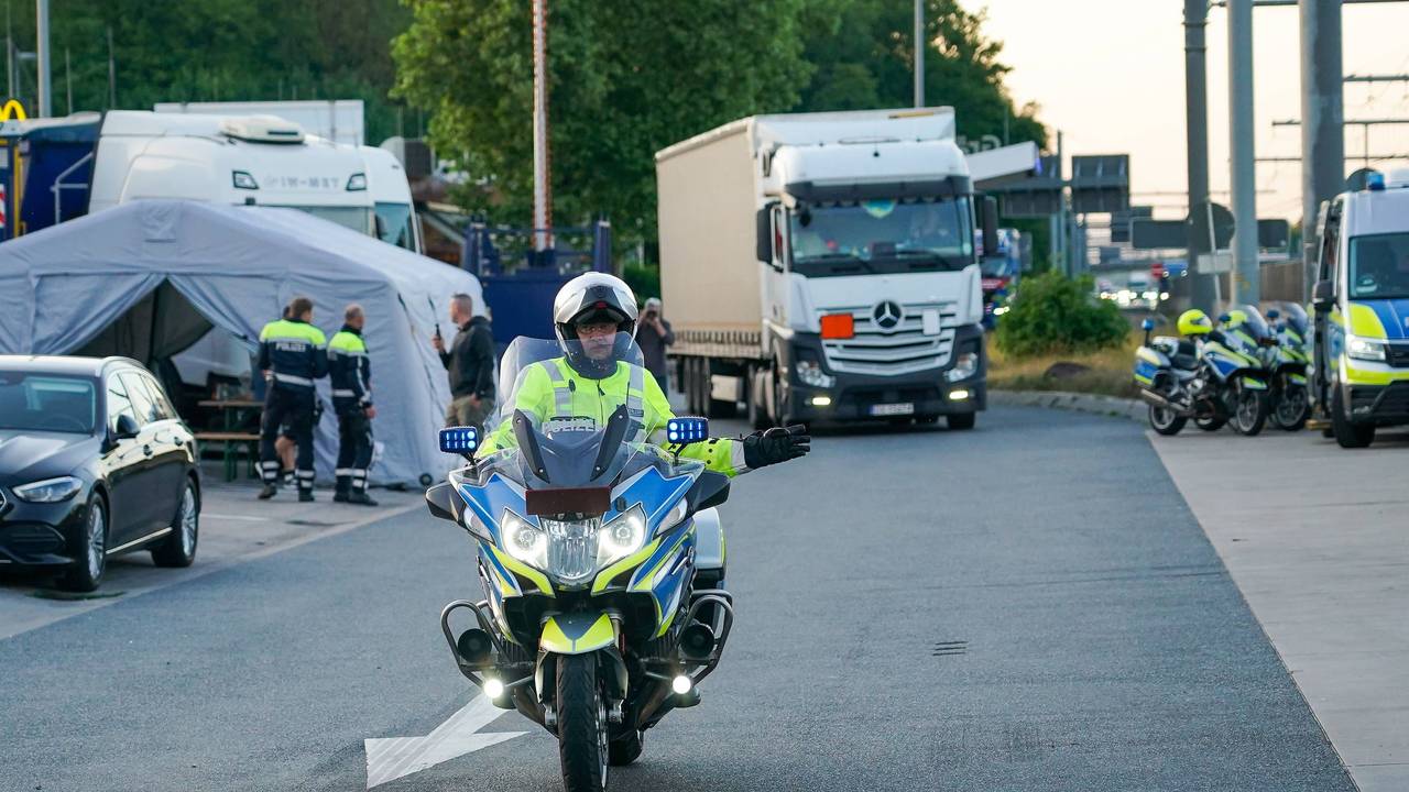 Ein Motorrad-Polizist vor einem Lkw.