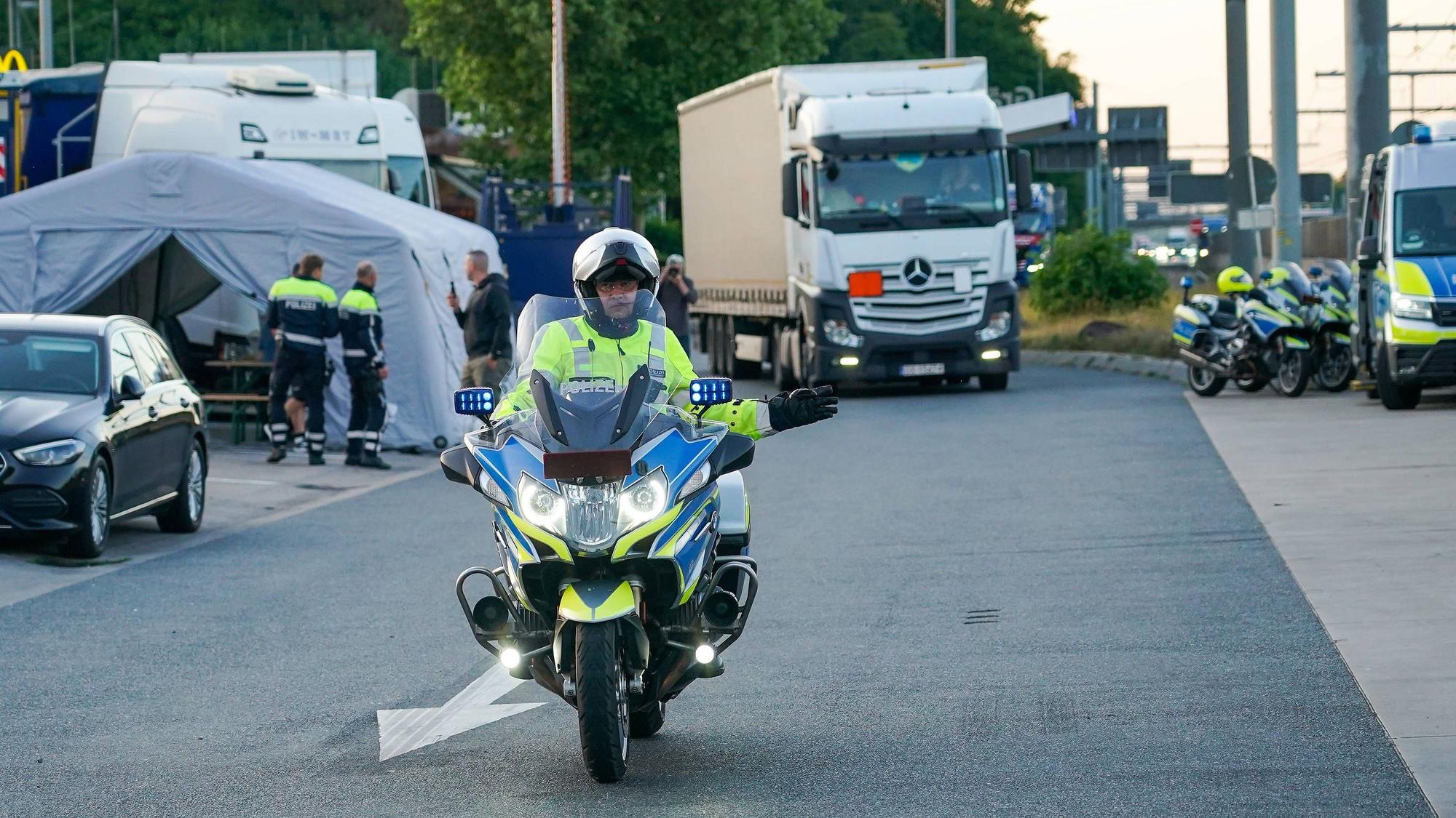 Ein Motorrad-Polizist vor einem Lkw.