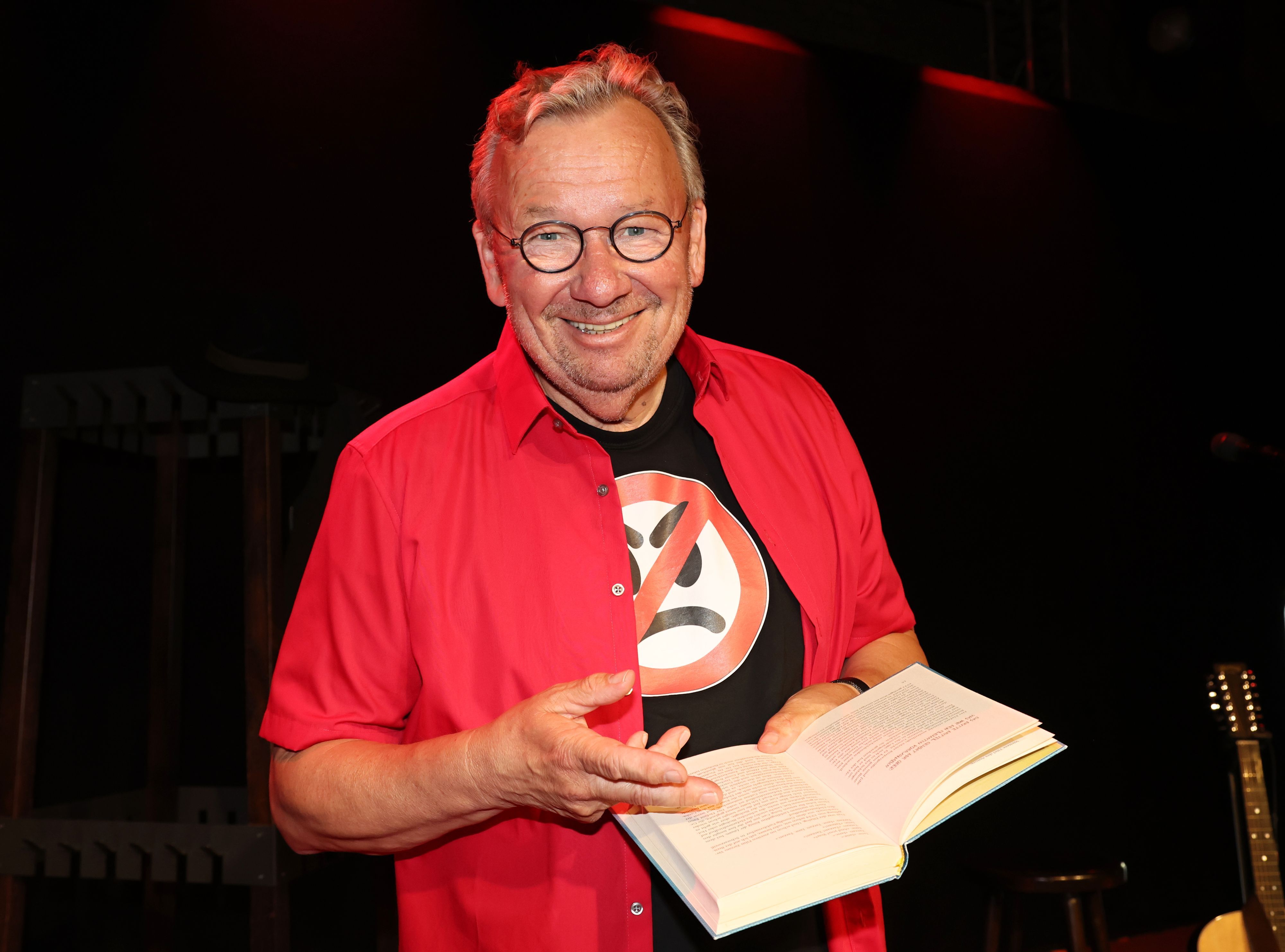 Bernd Stelter steht mit seinem Buch auf der Bühne.