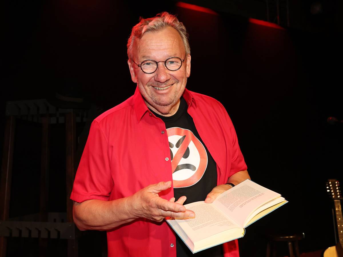 Bernd Stelter steht mit seinem Buch auf der Bühne.