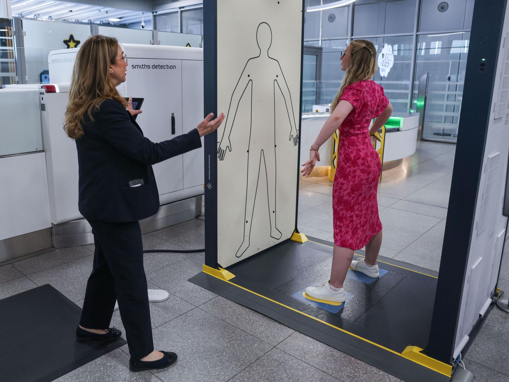 Die Mitarbeiterin einer Sicherheitsfirma leitet im Sicherheitsbereich am Flughafen Köln/Bonn eine Reisende in einen Körperscanner. Eine neue Anlage mit elf modernen CT-Kontrollspuren und Scannern soll künftig für schnellere, komfortablere und effizientere Abläufe sorgen.