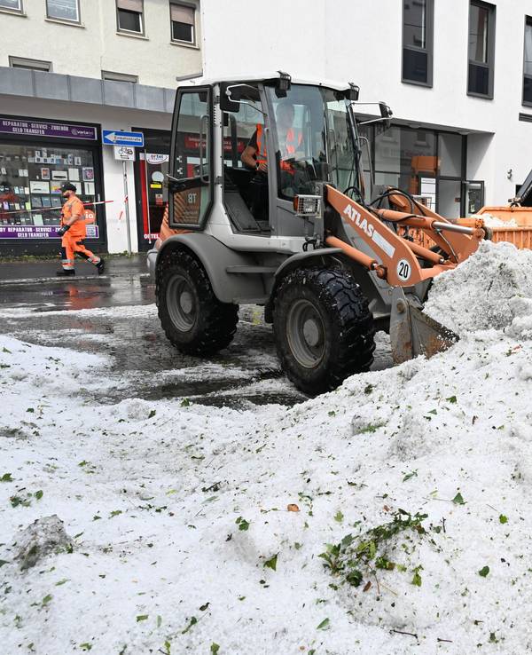 Mitarbeiter der Stadtreinigung entfernen in Reutlingen Hagel, der nach einem Unwetter in der Innenstadt aufgetürmt wurde.