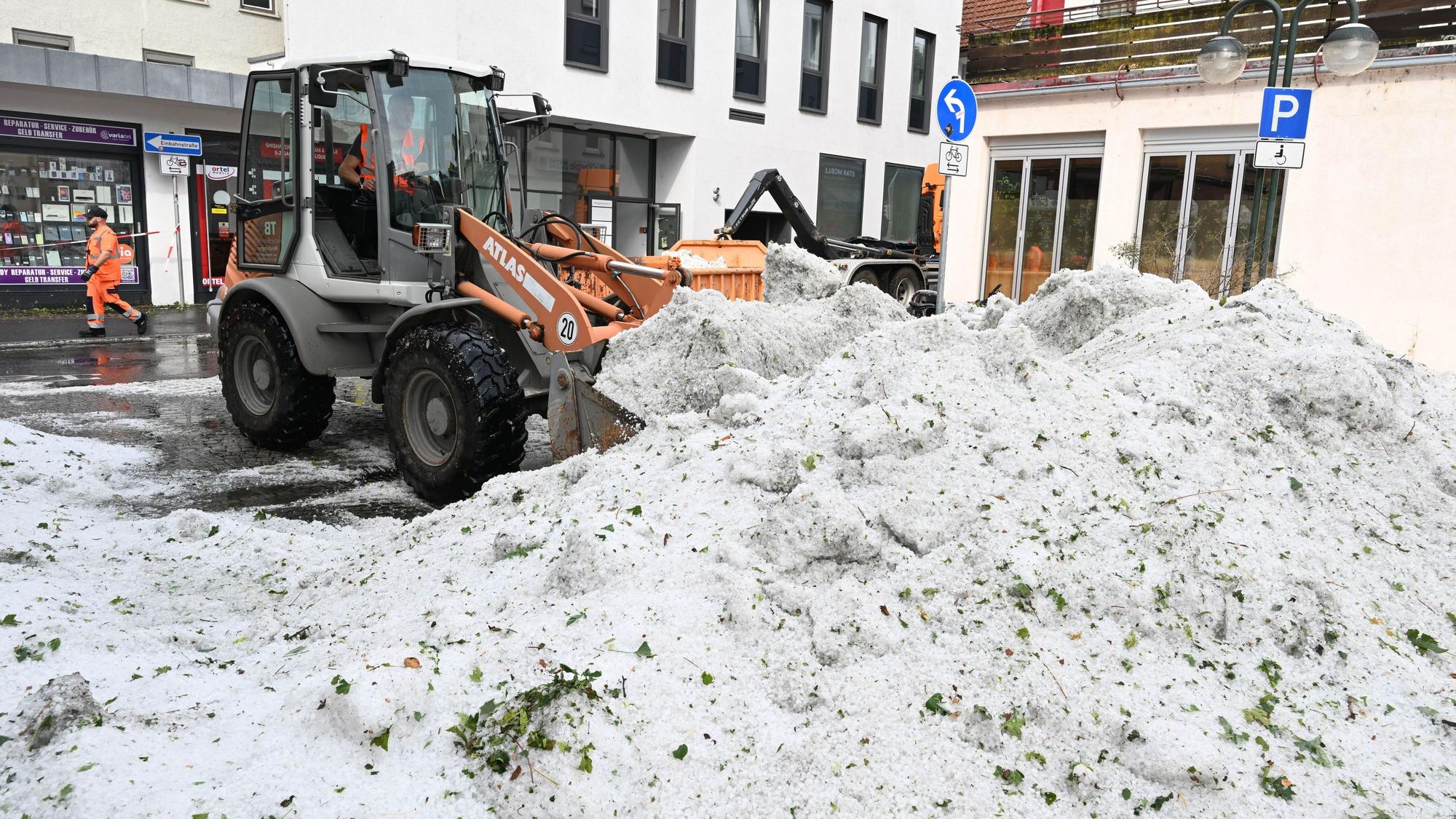 Mitarbeiter der Stadtreinigung entfernen in Reutlingen Hagel, der nach einem Unwetter in der Innenstadt aufgetürmt wurde.