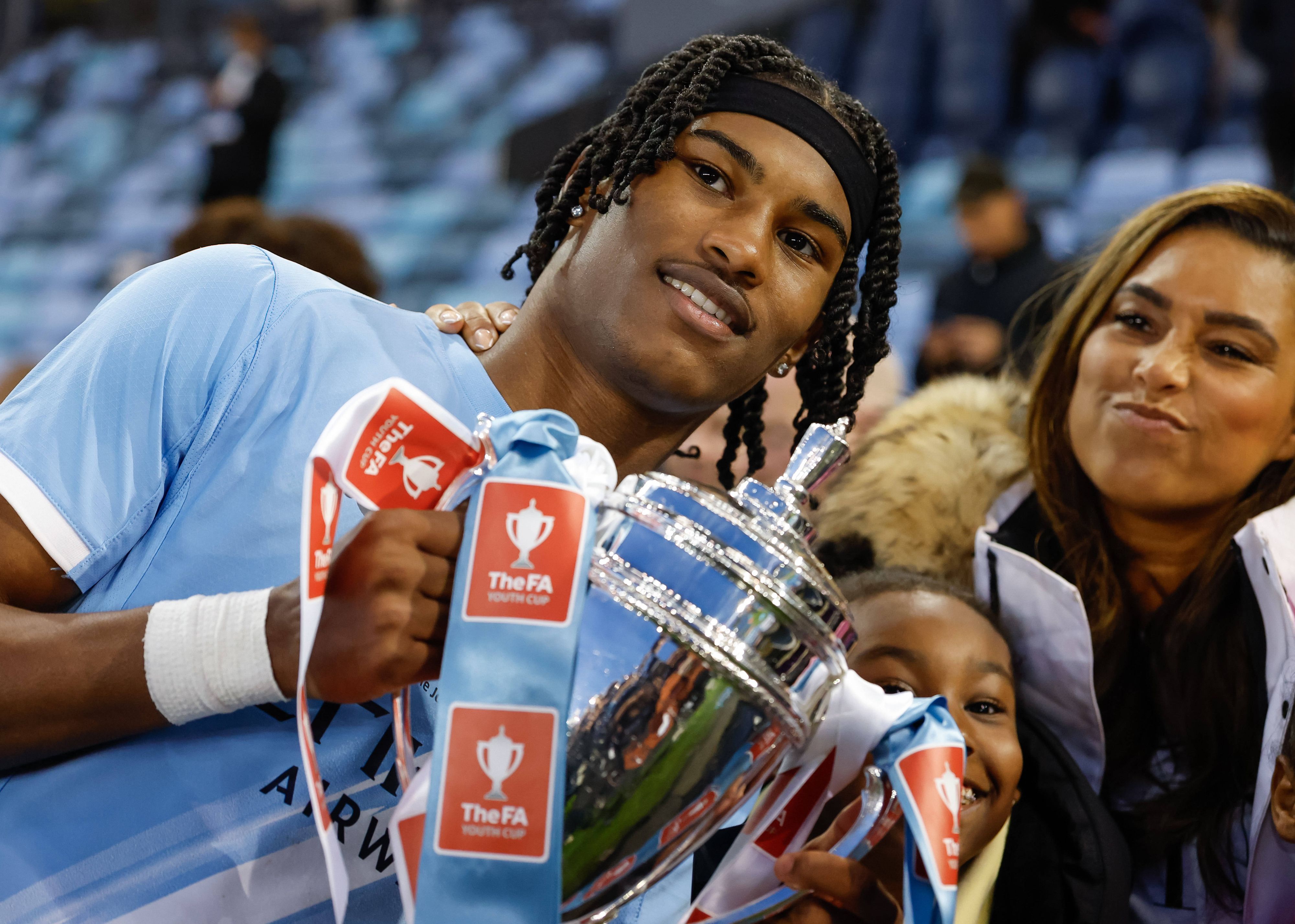 Reigan Heskey von Manchester City feiert mit seiner Familie den Gewinn des FA-Youth-Cup und hält eine Trophäe hoch.