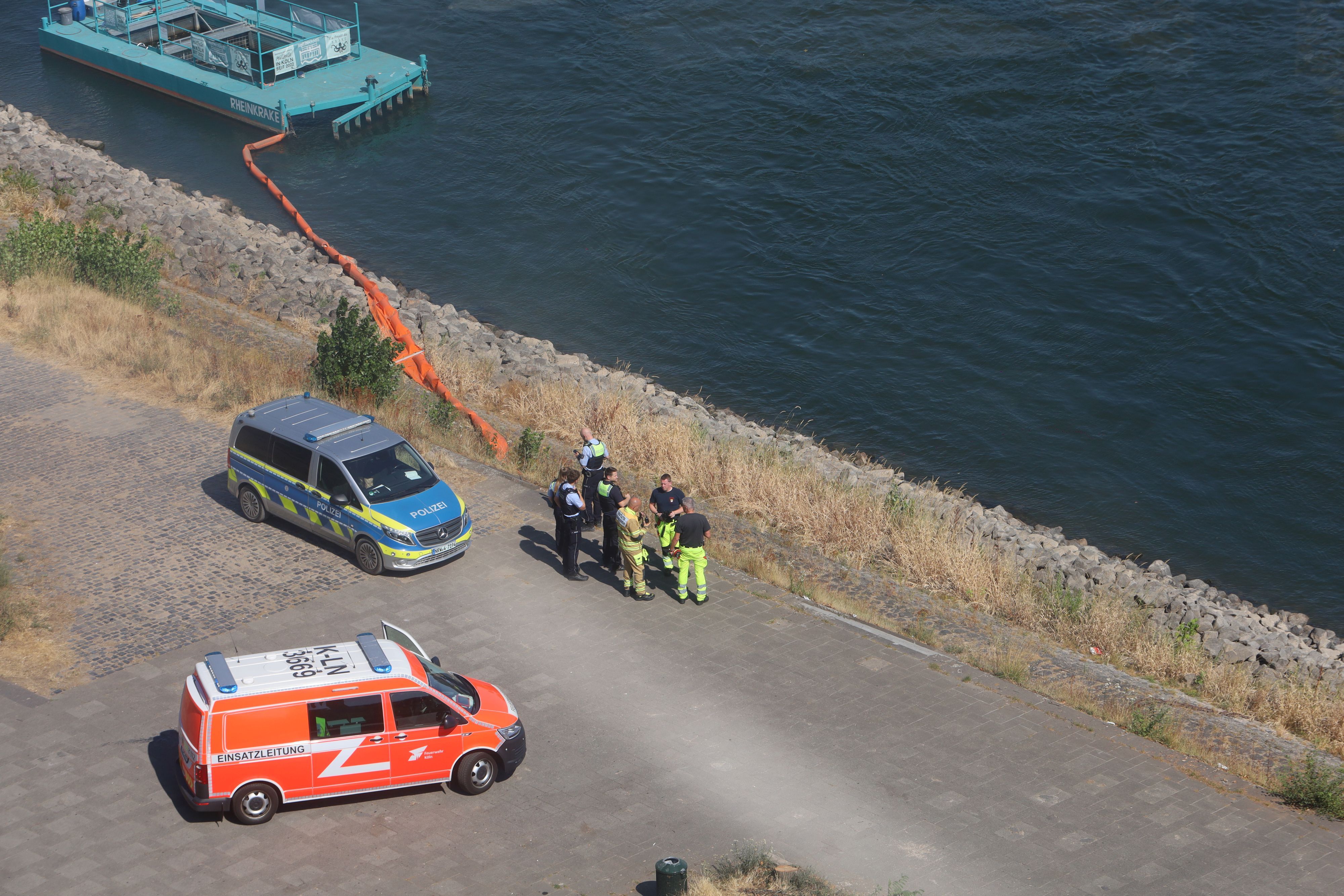 Einsatzkräfte stehen am Rheinufer.