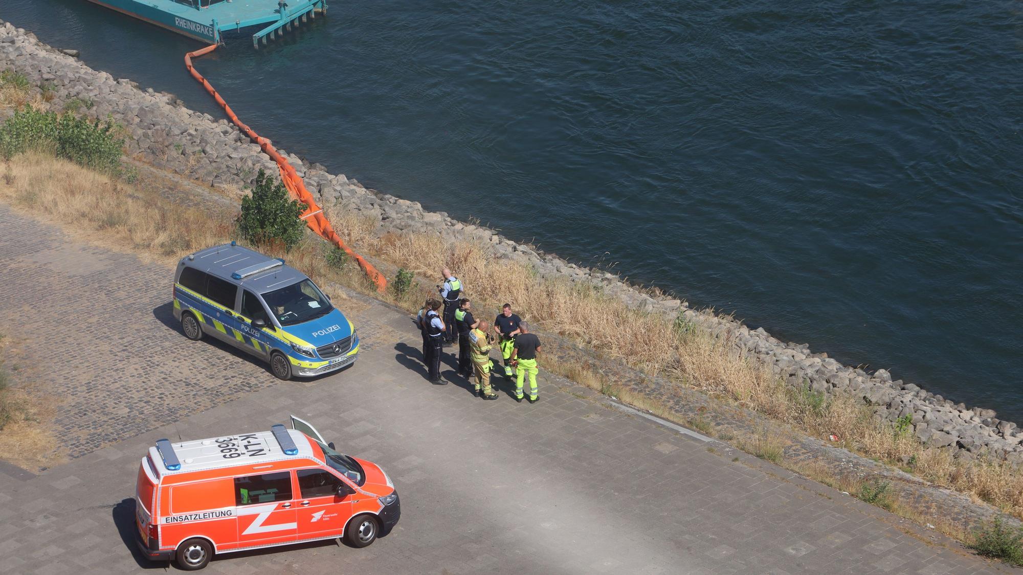Einsatzkräfte stehen am Rheinufer.