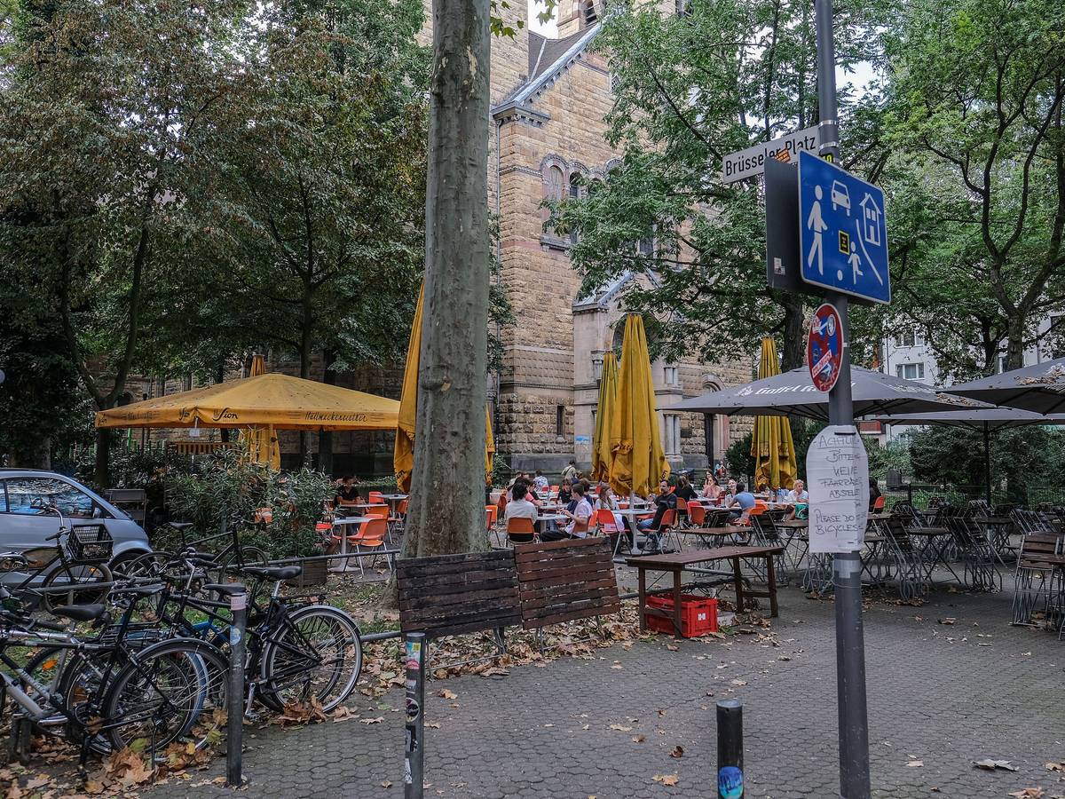 Menschen sitzen am Brüsseler Platz in einem Straßencafé. Um den Platz gibt es seit langer Zeit Streit. (Archivfoto)