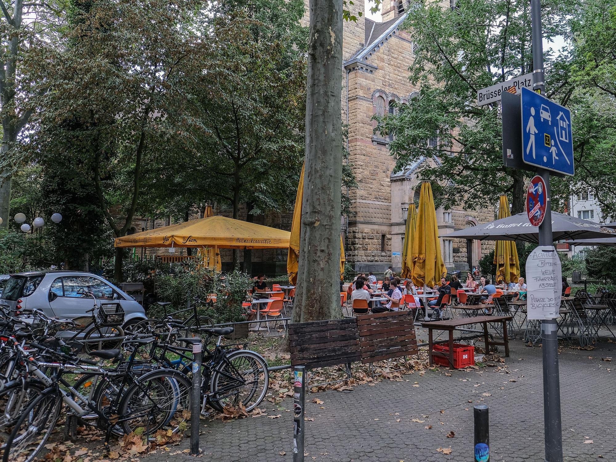 Menschen sitzen am Brüsseler Platz in einem Straßencafé. Um den Platz gibt es seit langer Zeit Streit. (Archivfoto)