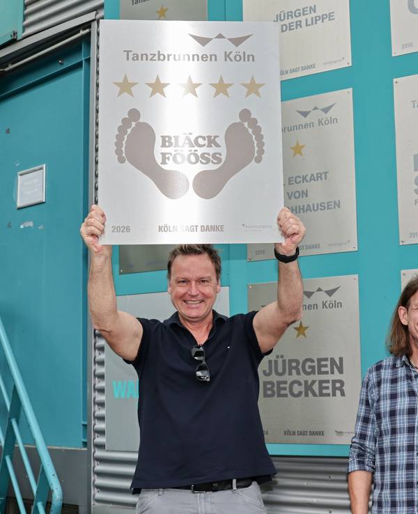 Mirko Bäumer von den Bläck Fööss zeigt die Ehrentafel zum 50. Konzert im Tanzbrunnen.