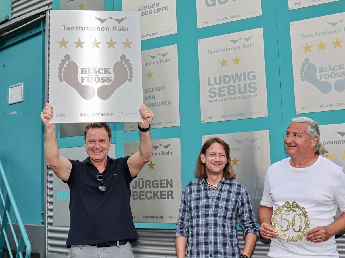 Mirko Bäumer von den Bläck Fööss zeigt die Ehrentafel zum 50. Konzert im Tanzbrunnen.