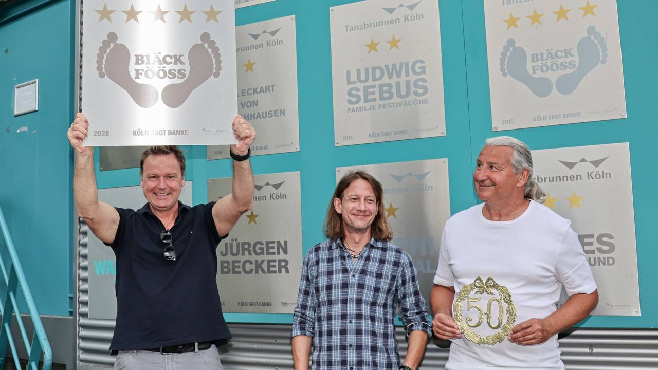 Mirko Bäumer von den Bläck Fööss zeigt die Ehrentafel zum 50. Konzert im Tanzbrunnen.