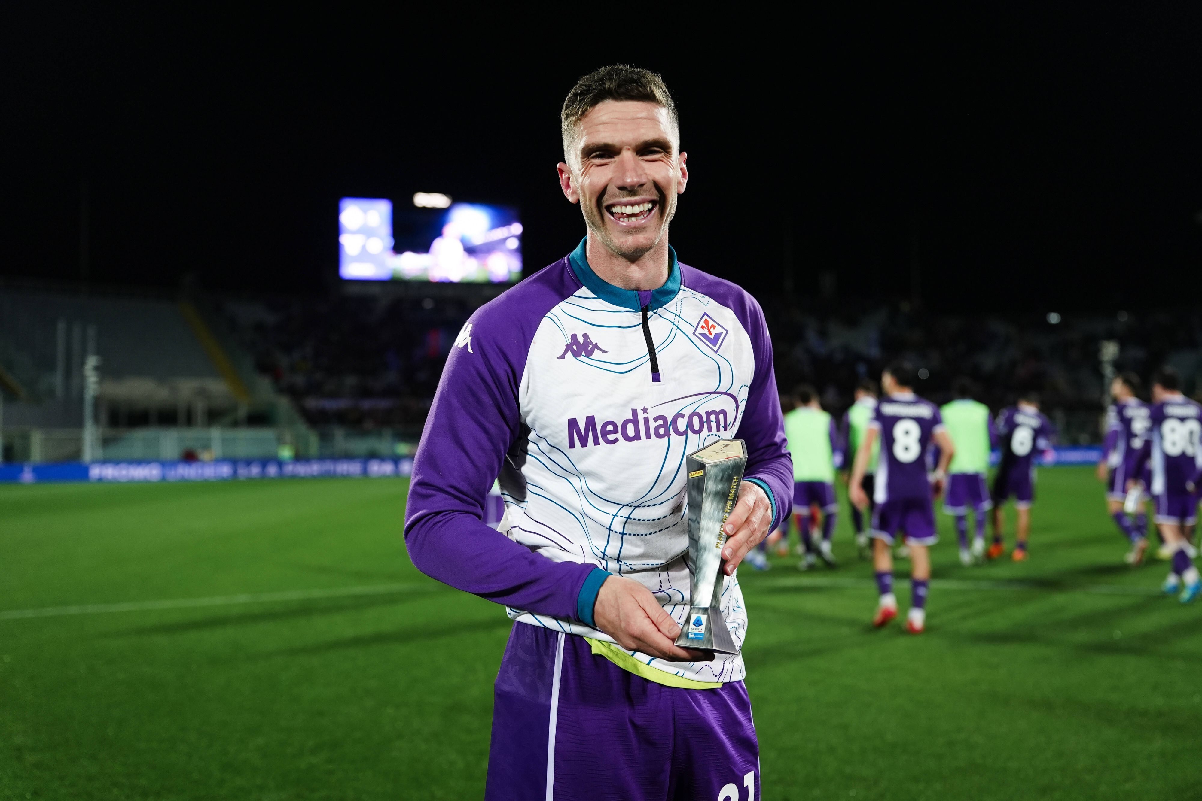 Robin Gosens hält eine kleine Trophäe in die Kamera und lächelt.