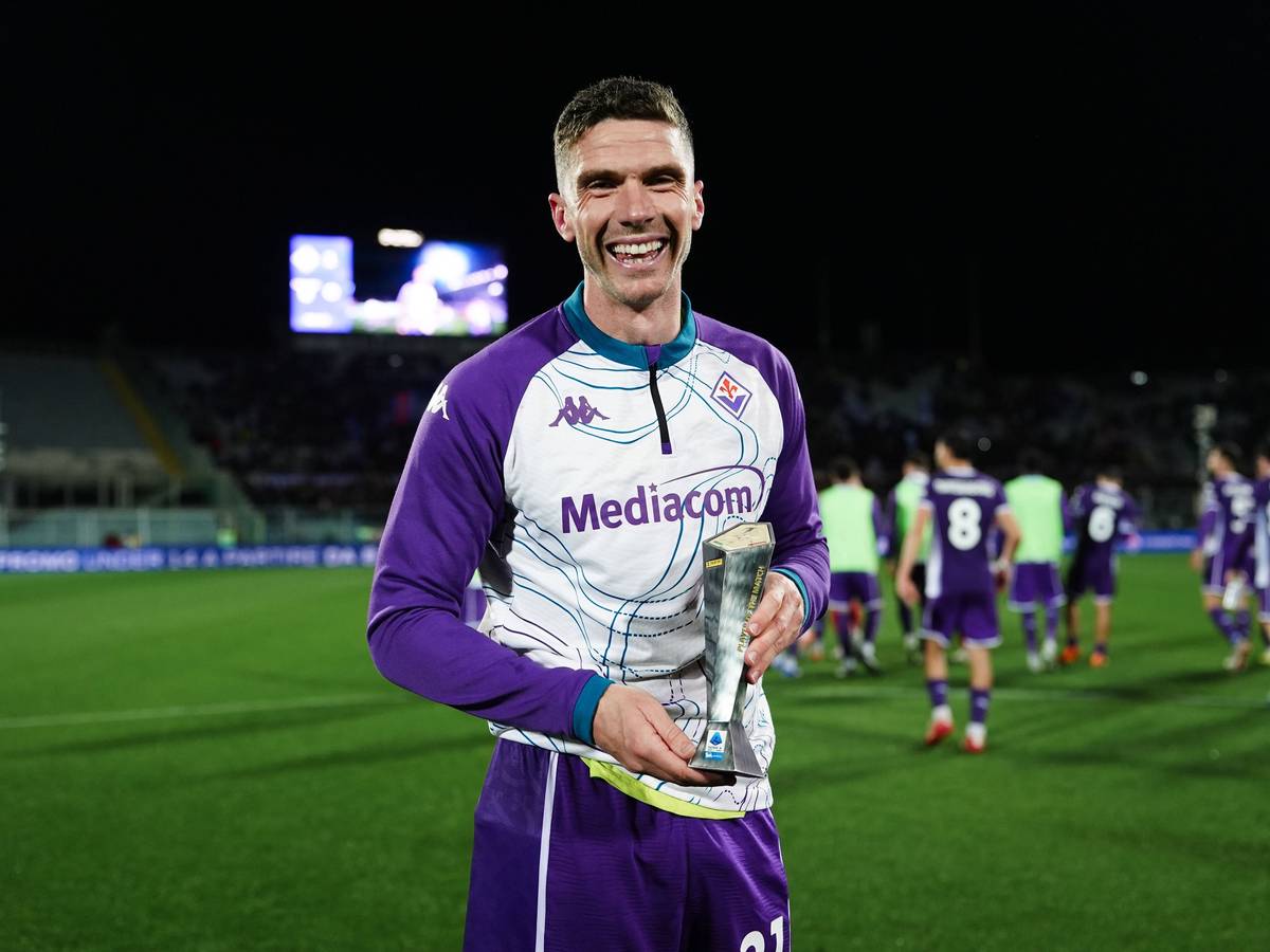 Robin Gosens hält eine kleine Trophäe in die Kamera und lächelt.