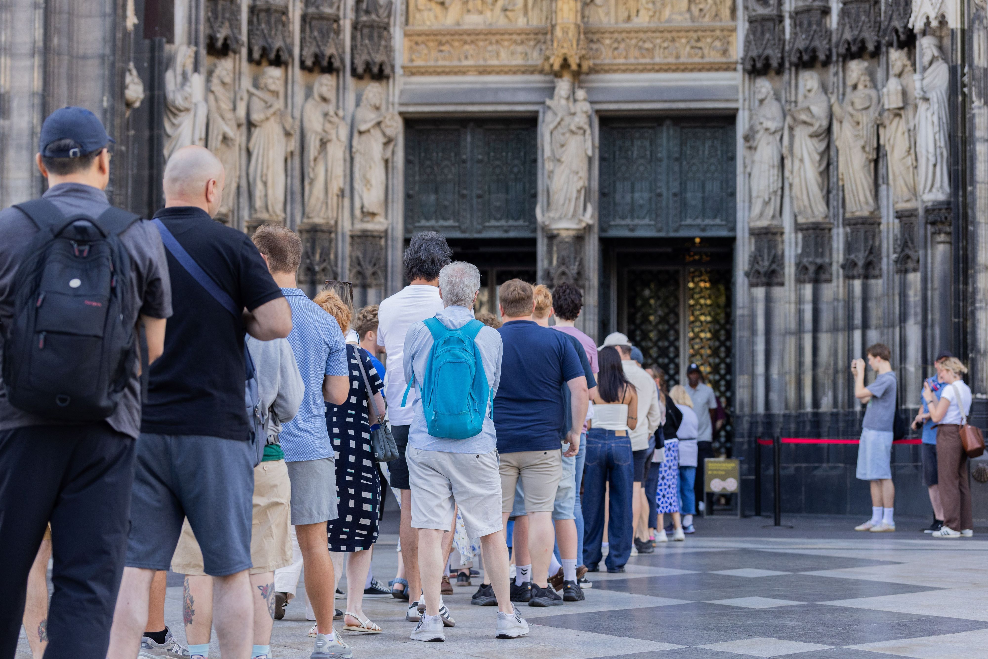 Vor dem Haupteingang des Kölner Doms hat sich eine lange Schlange gebildet.
