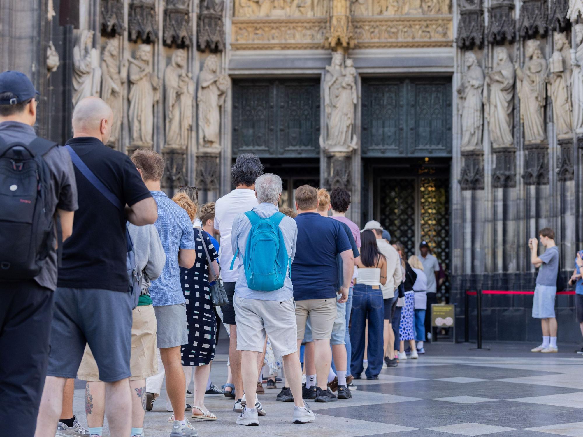Touristen stehen vor dem Haupteingang des Kölner Doms.