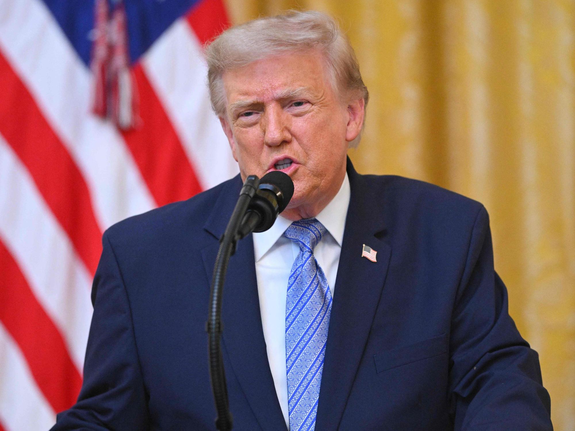 Donald Trump spricht bei einer Rede an die Nation in ein Mikrofon, im Hintergrund die US-Flagge.