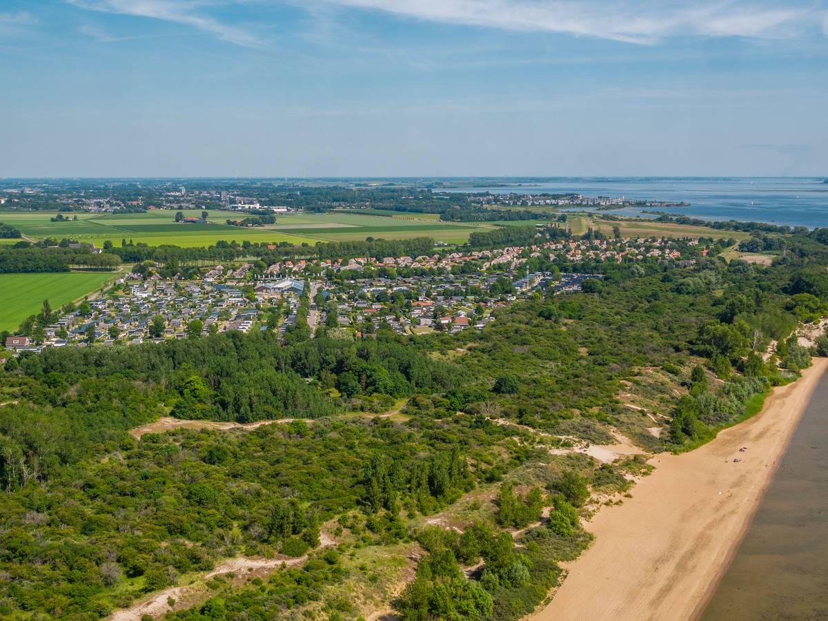 Ein Strand mit einer Feriensiedlung in einem kleinen Waldstück