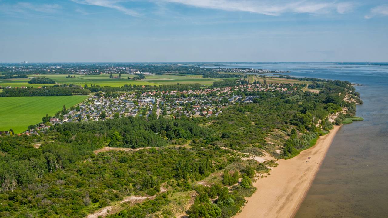 Ein Strand mit einer Feriensiedlung in einem kleinen Waldstück
